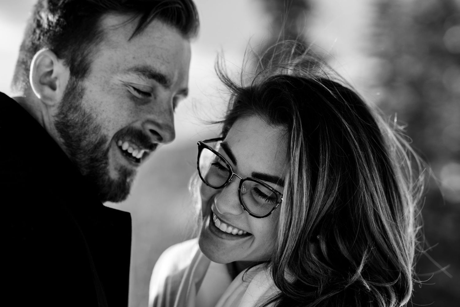A joyful black and white close-up moment of shared laughter between a couple.
