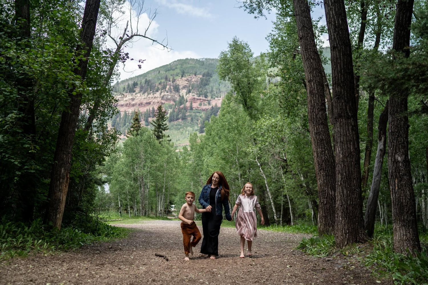 People walking together on tree-lined path with mountain views. Photographed in Telluride Colorado