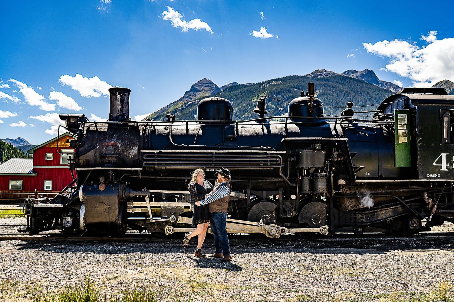 Engagement photo with Durango and Silverton train in mountain landscape backdrop.