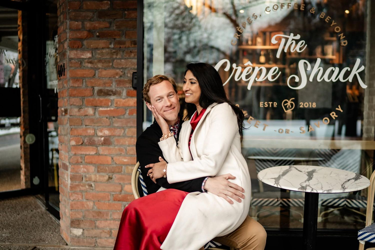Couple cuddles in close outside of a cafe in Aspen Colorado. Captured by Delta, Colorado photographers