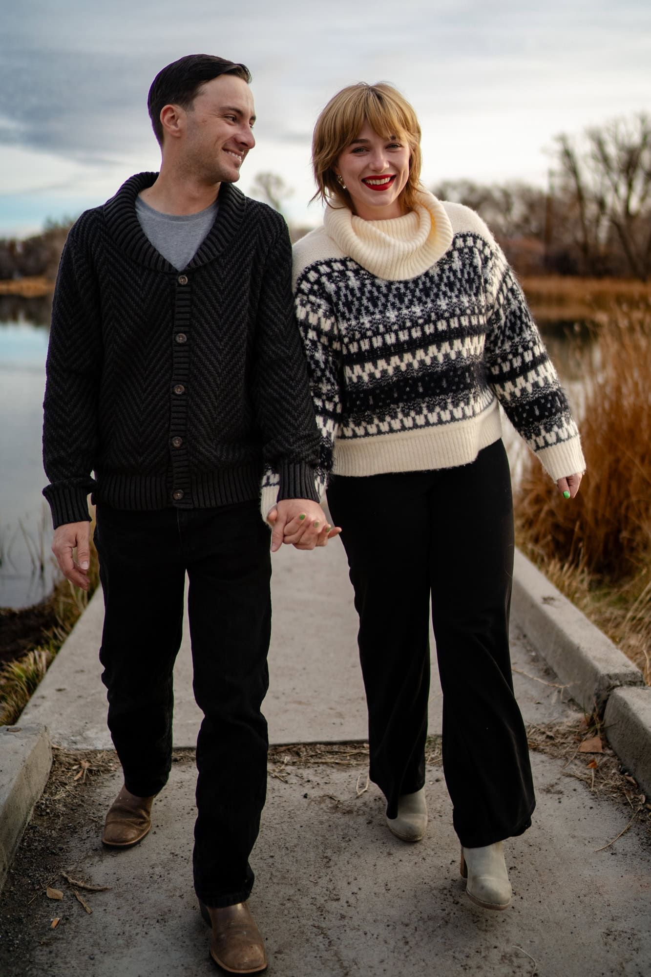 A happy couple shares a laugh while walking together on a pathway near water.