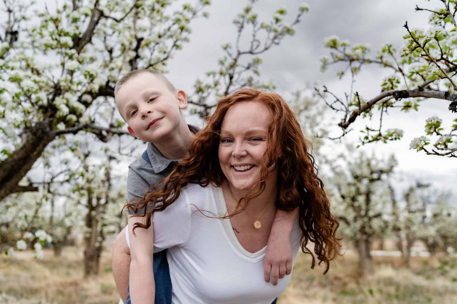Playful moment between parent and child in a blooming orchard.