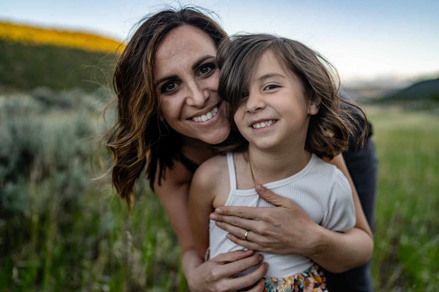 Loving embrace captured against golden wildflower field at sunset.