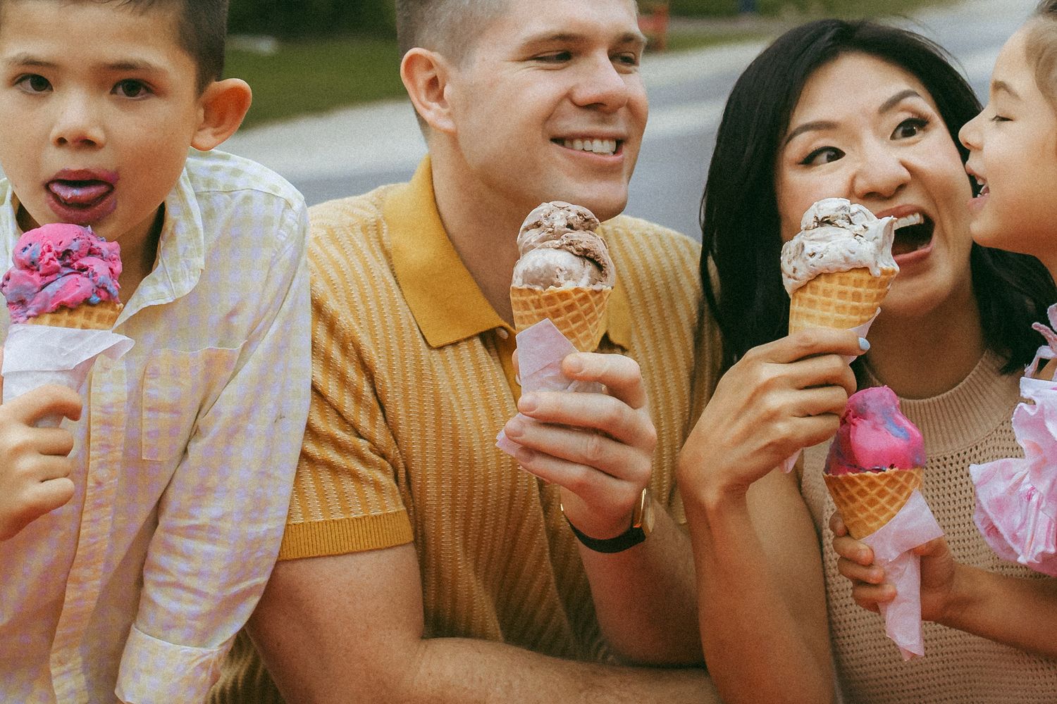 A group enjoying colorful ice cream cones together on a sunny day outdoors.