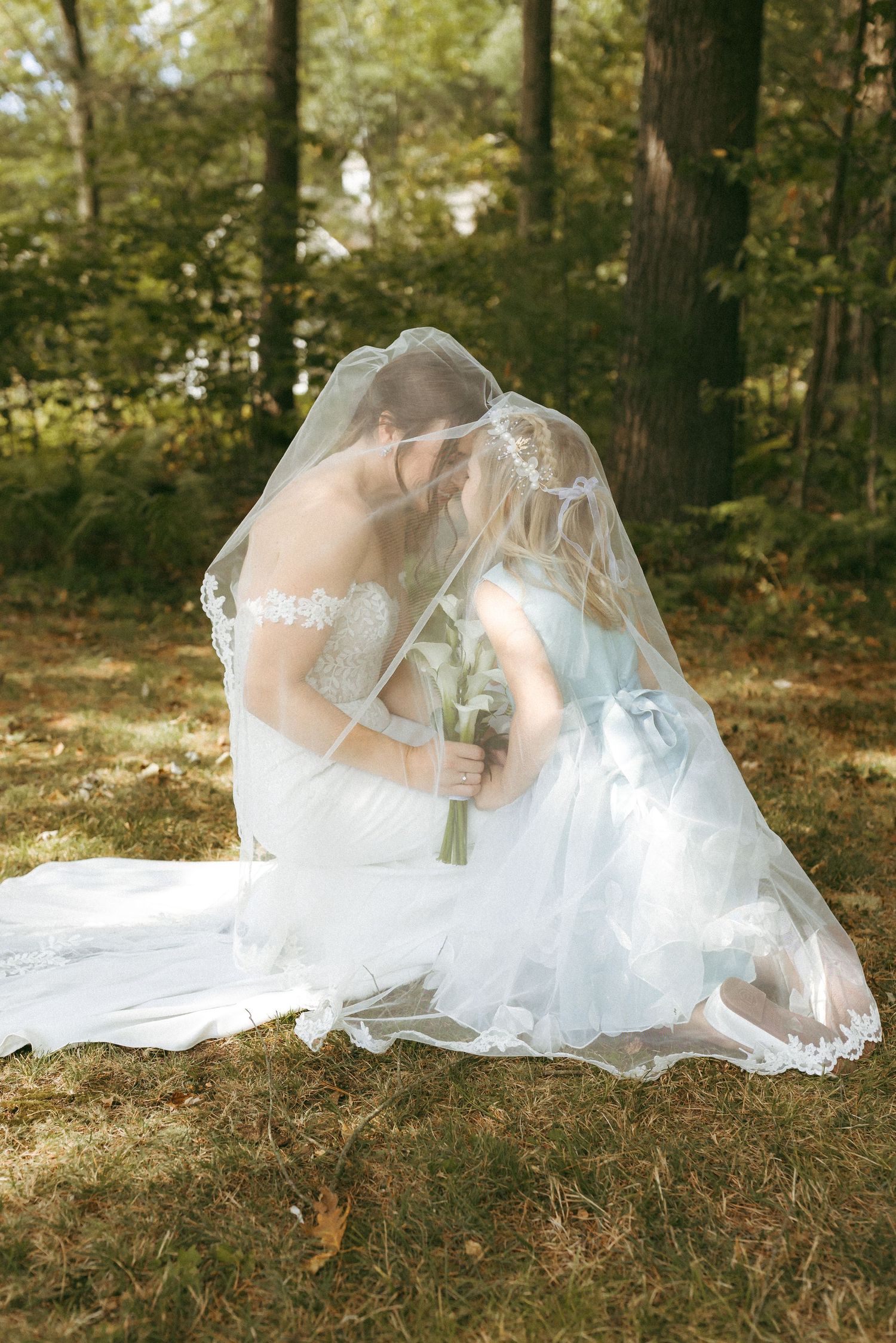 A dreamy outdoor wedding photo showing a flowing veil surrounding a mother and her daughter.