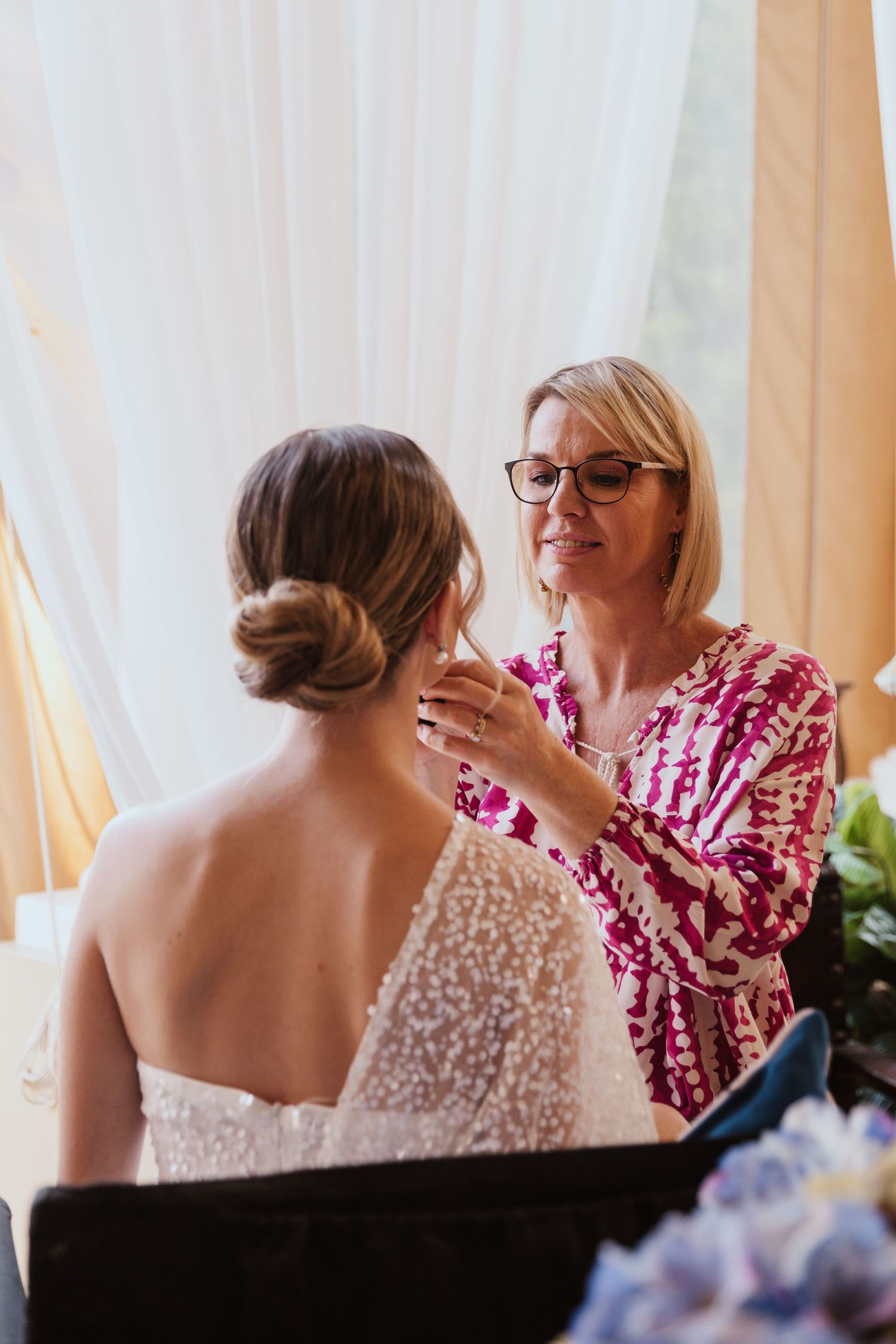 Wedding preparation scene with bridal gown and flowing white curtains in natural light.