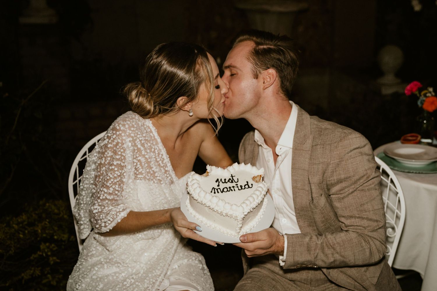 Romantic moment shared over heart-shaped wedding cake at outdoor reception.