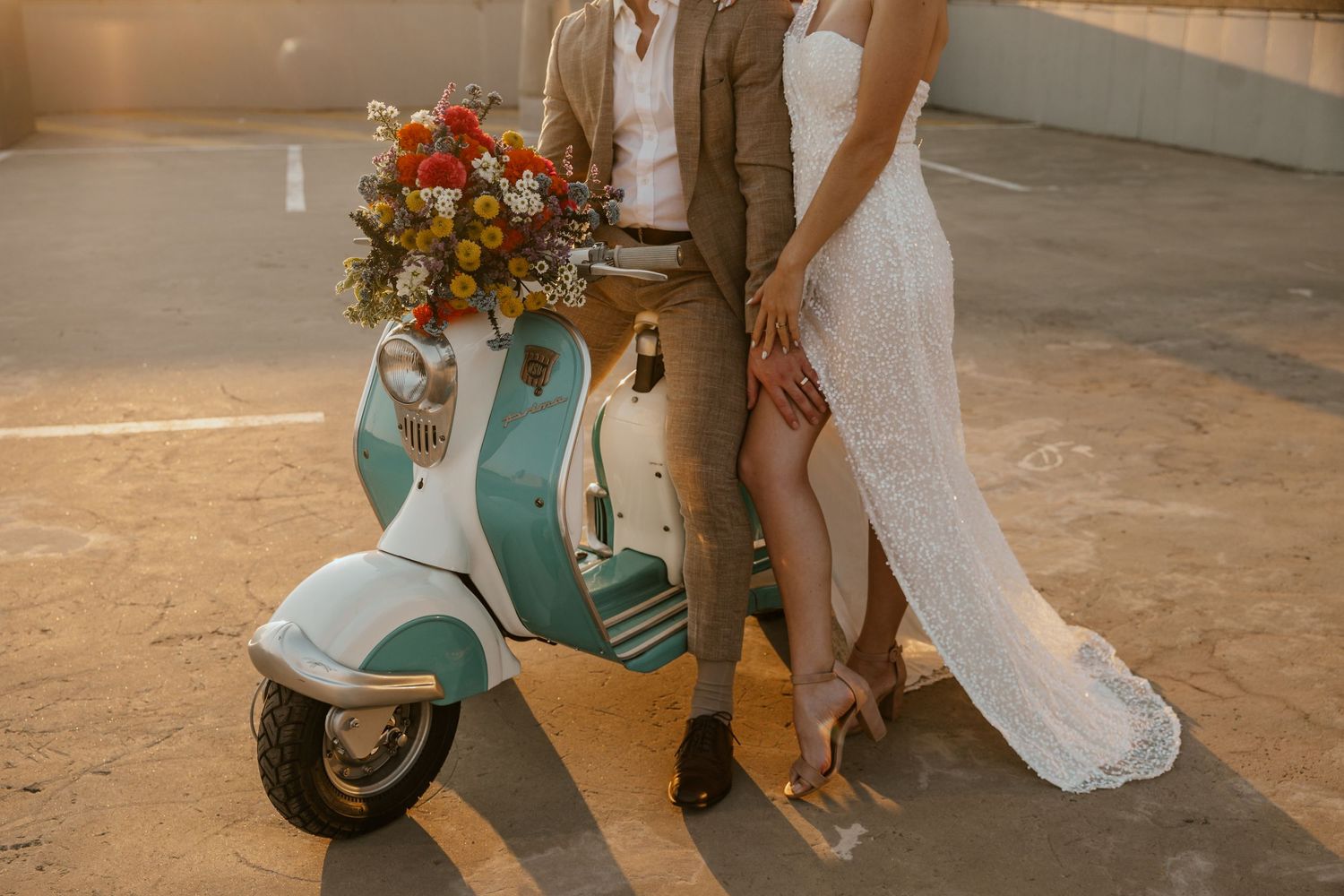 A wedding couple poses with a vintage mint scooter and colorful floral arrangement.