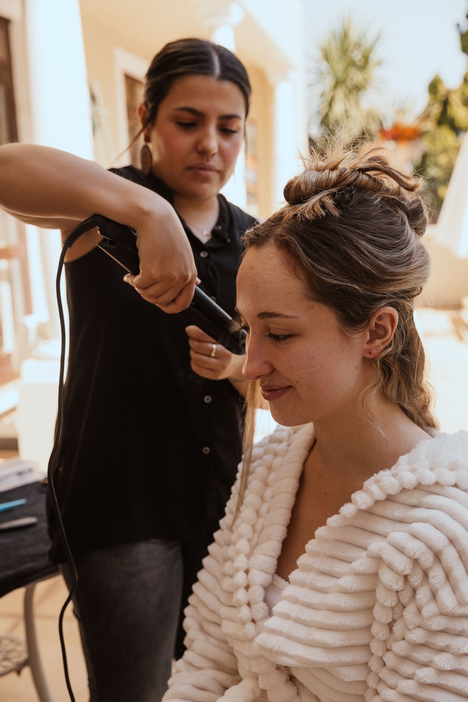 Hair stylist working on elegant bridal updo during wedding preparations.