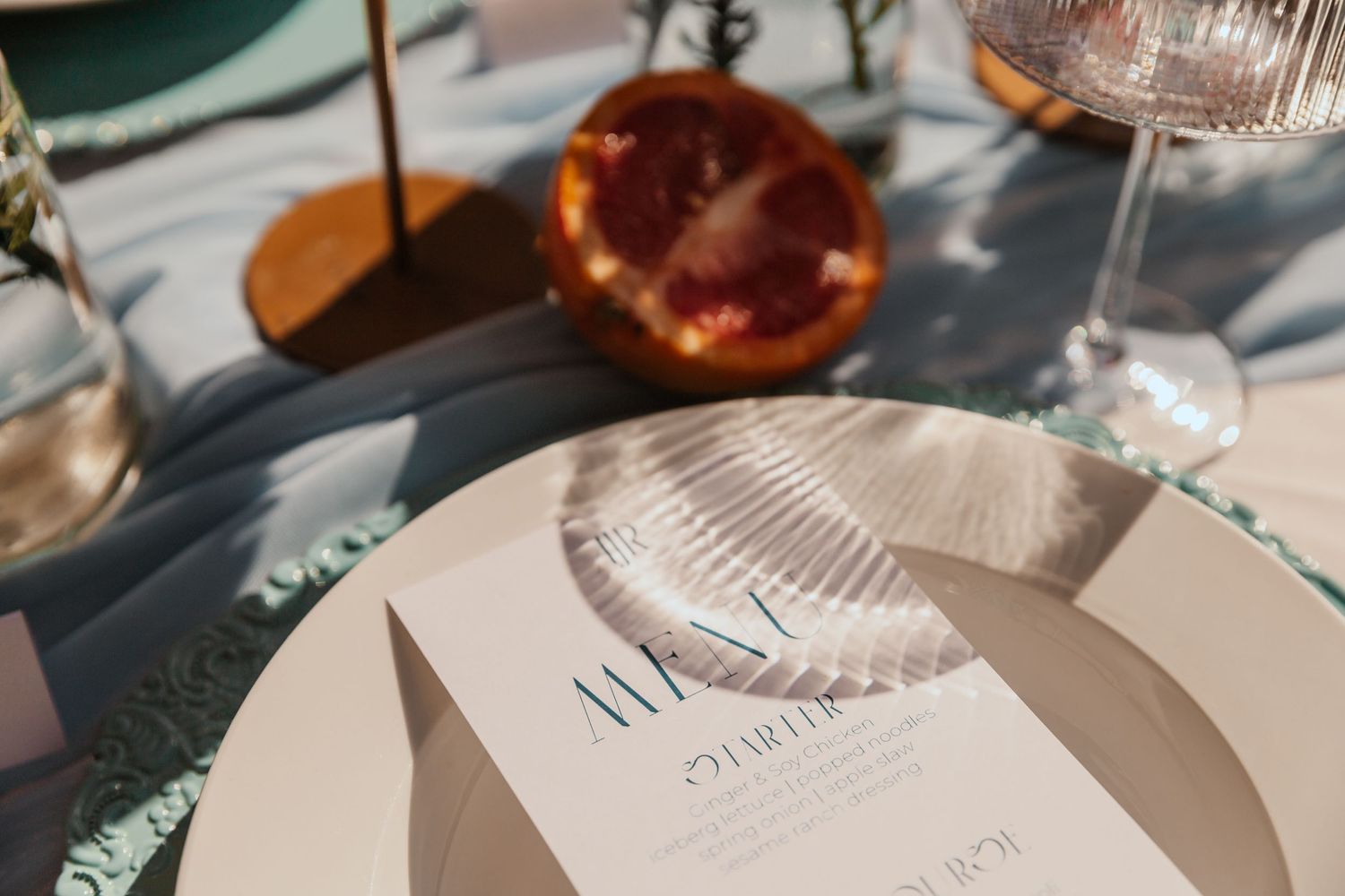 Wedding menu card and place setting with grapefruit slice on elegant table.