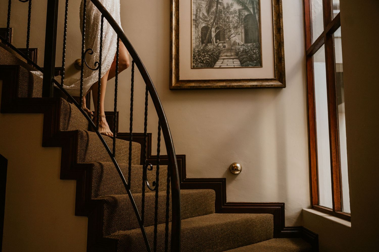 Vintage curved staircase with dark wood railings and carpeted steps.