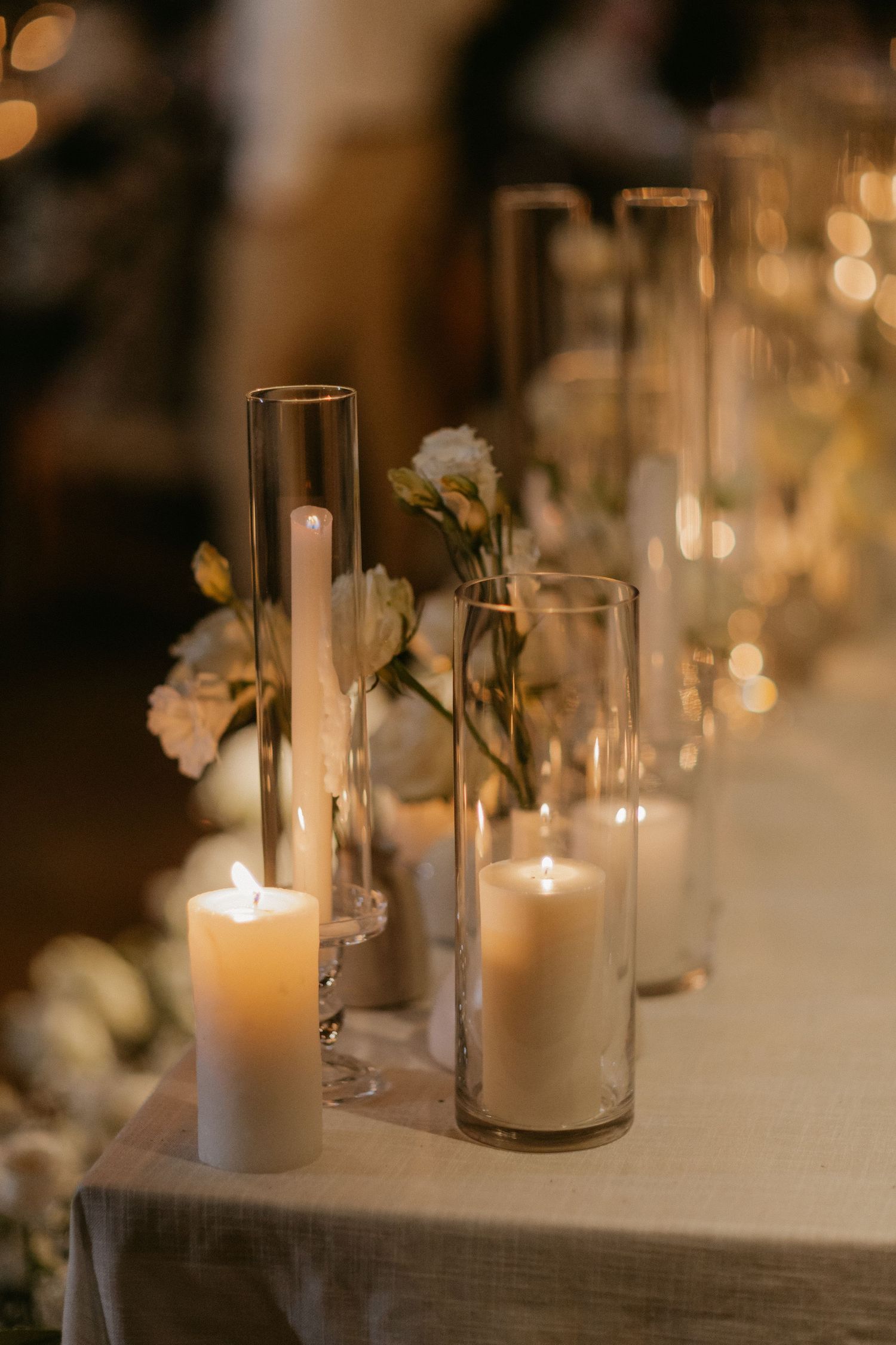 Elegant wedding reception table decorations featuring glowing white candles and floral arrangements in a romantic setting.