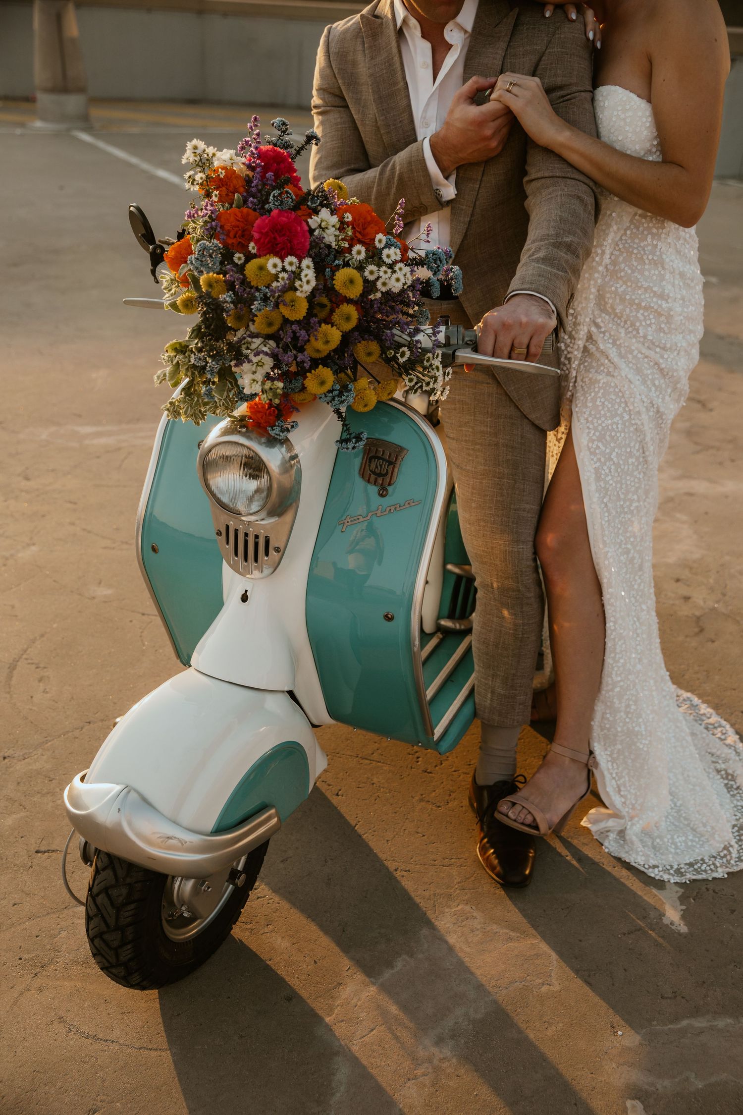 Close-up of turquoise scooter decorated with vibrant wedding bouquet.