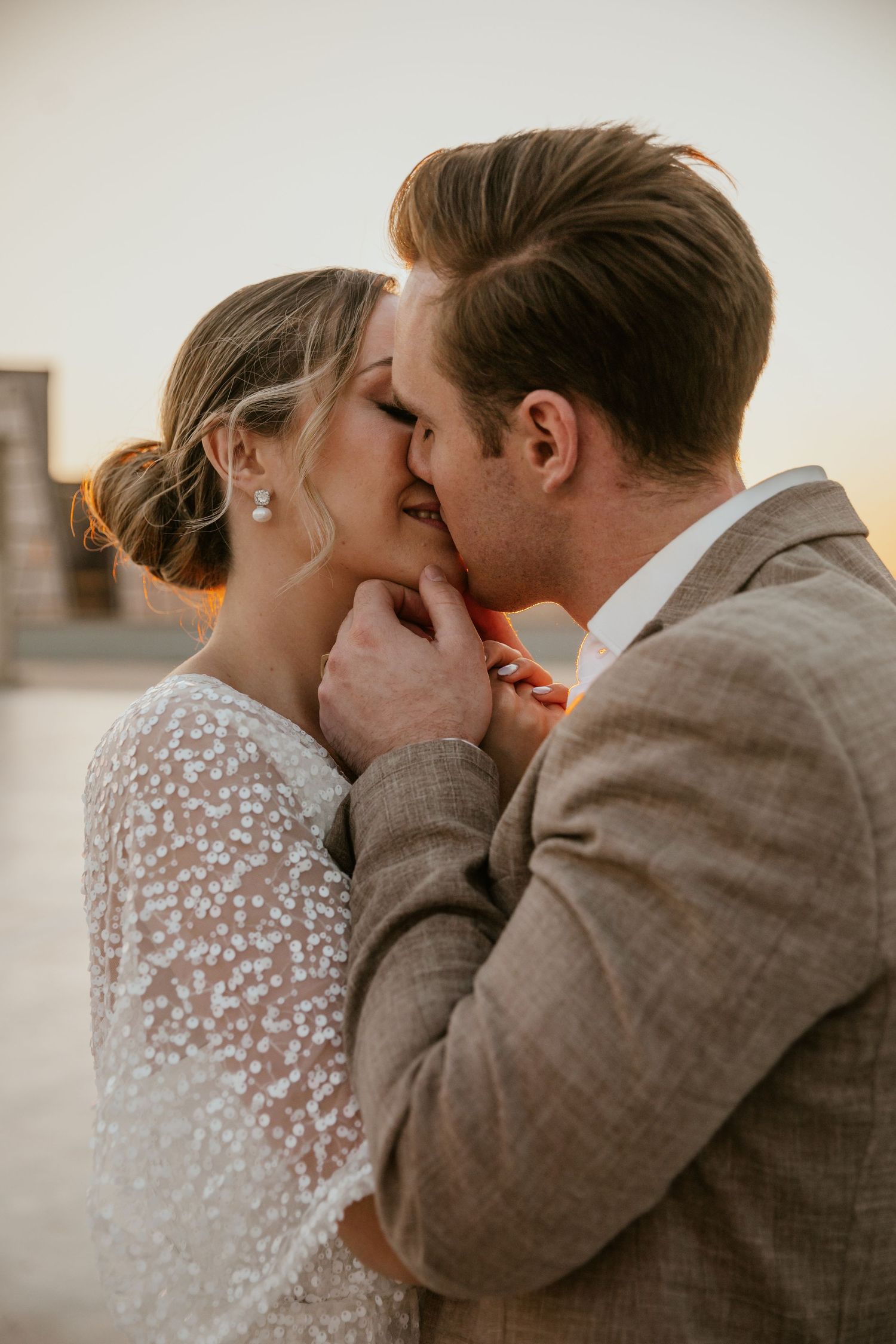 Romantic wedding moment with couple sharing an intimate kiss, bride wearing delicate lace sleeve dress.