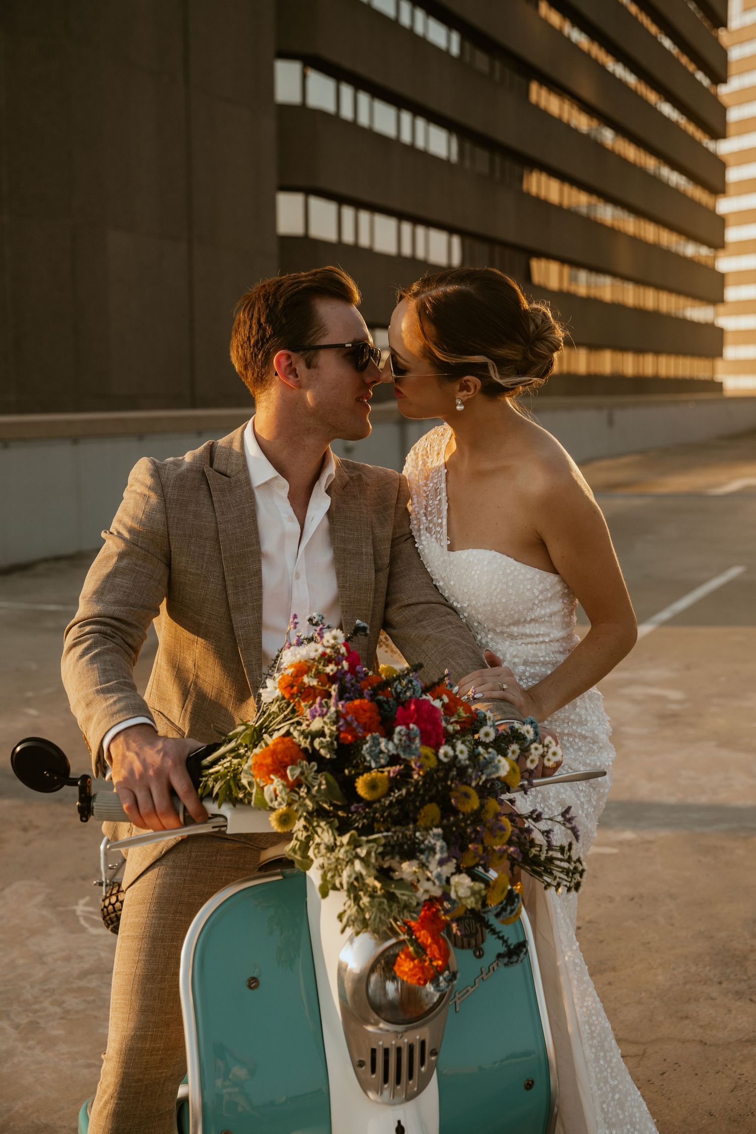 A romantic couple shares an intimate moment on a mint scooter with a colorful bouquet.