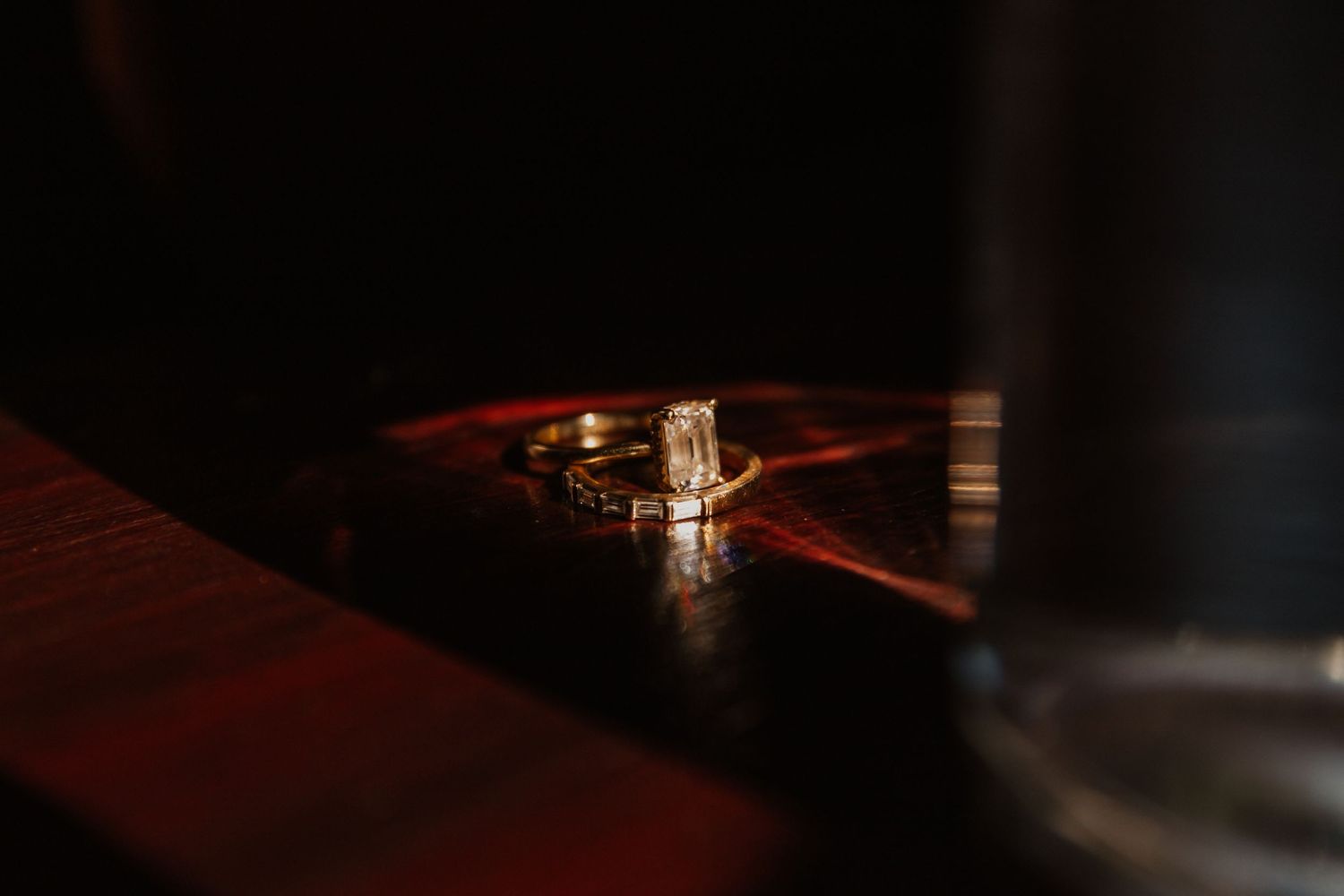 Wedding ring photographed in dramatic lighting on dark surface.