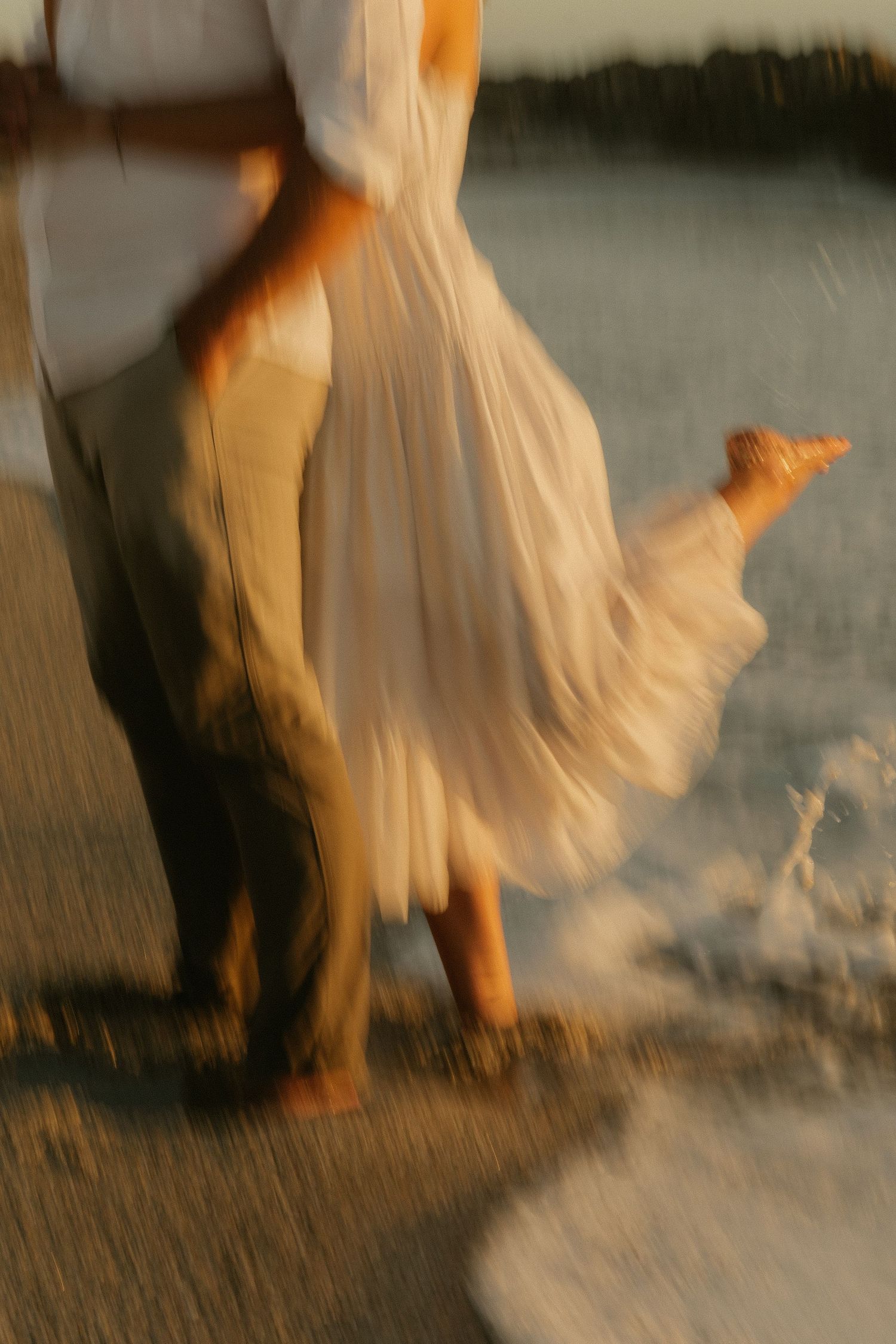 A blurred artistic photo of flowing white dress fabric on a beach.