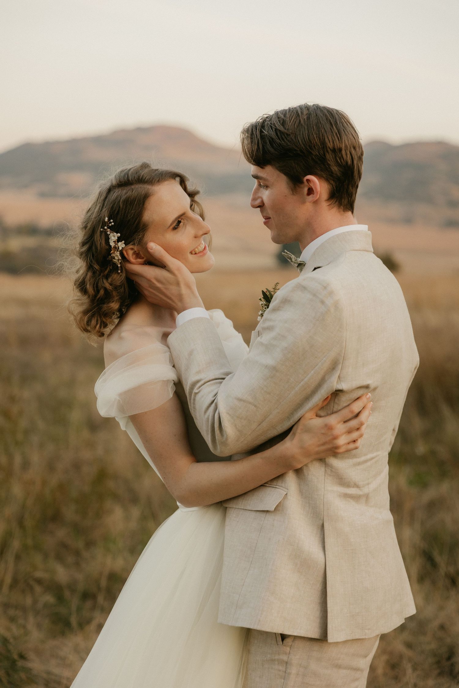 Intimate wedding photo of a couple embracing in a romantic moment against a scenic mountain backdrop.