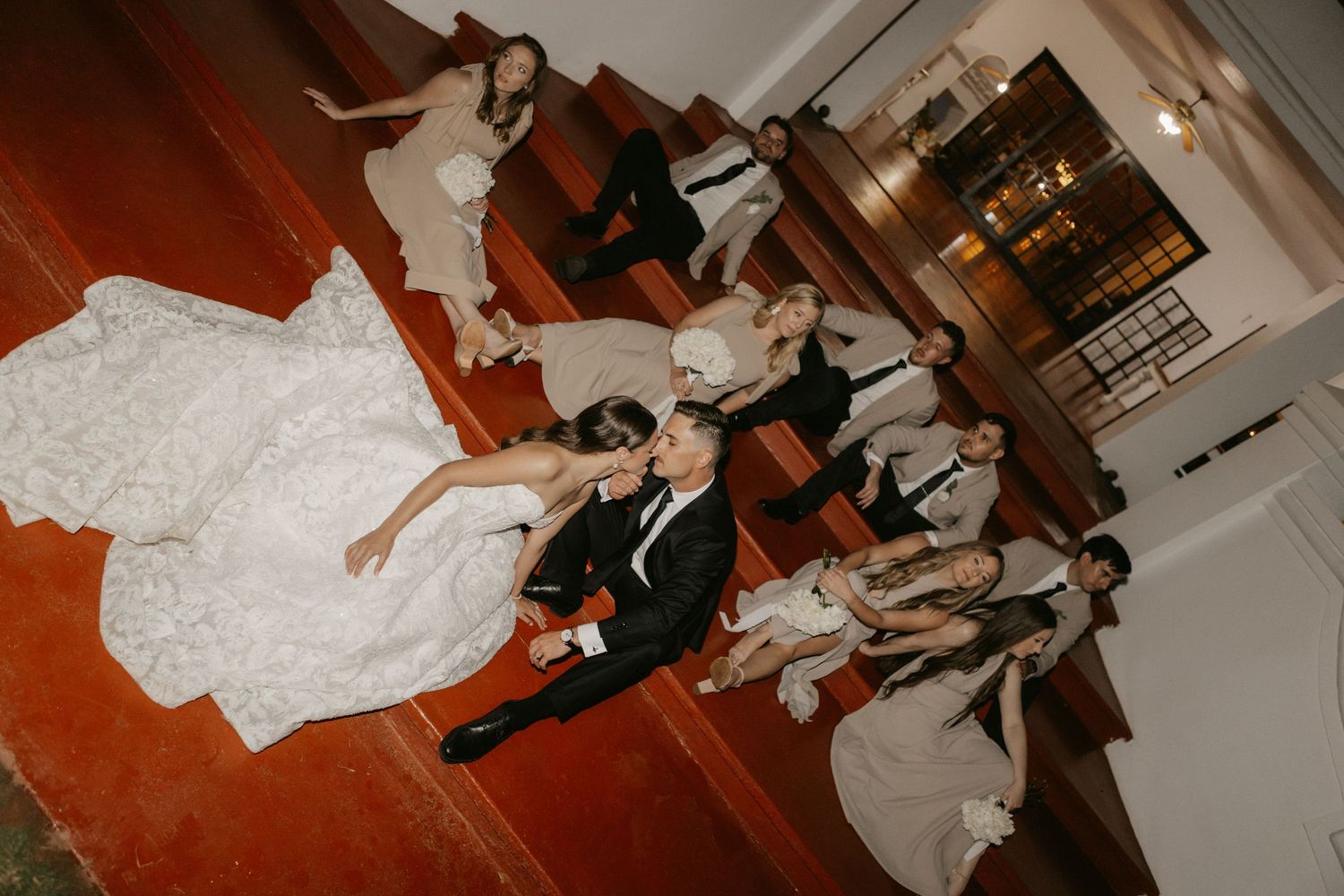 Wedding party posing from above in a church with bride in white gown and groom in tuxedo.