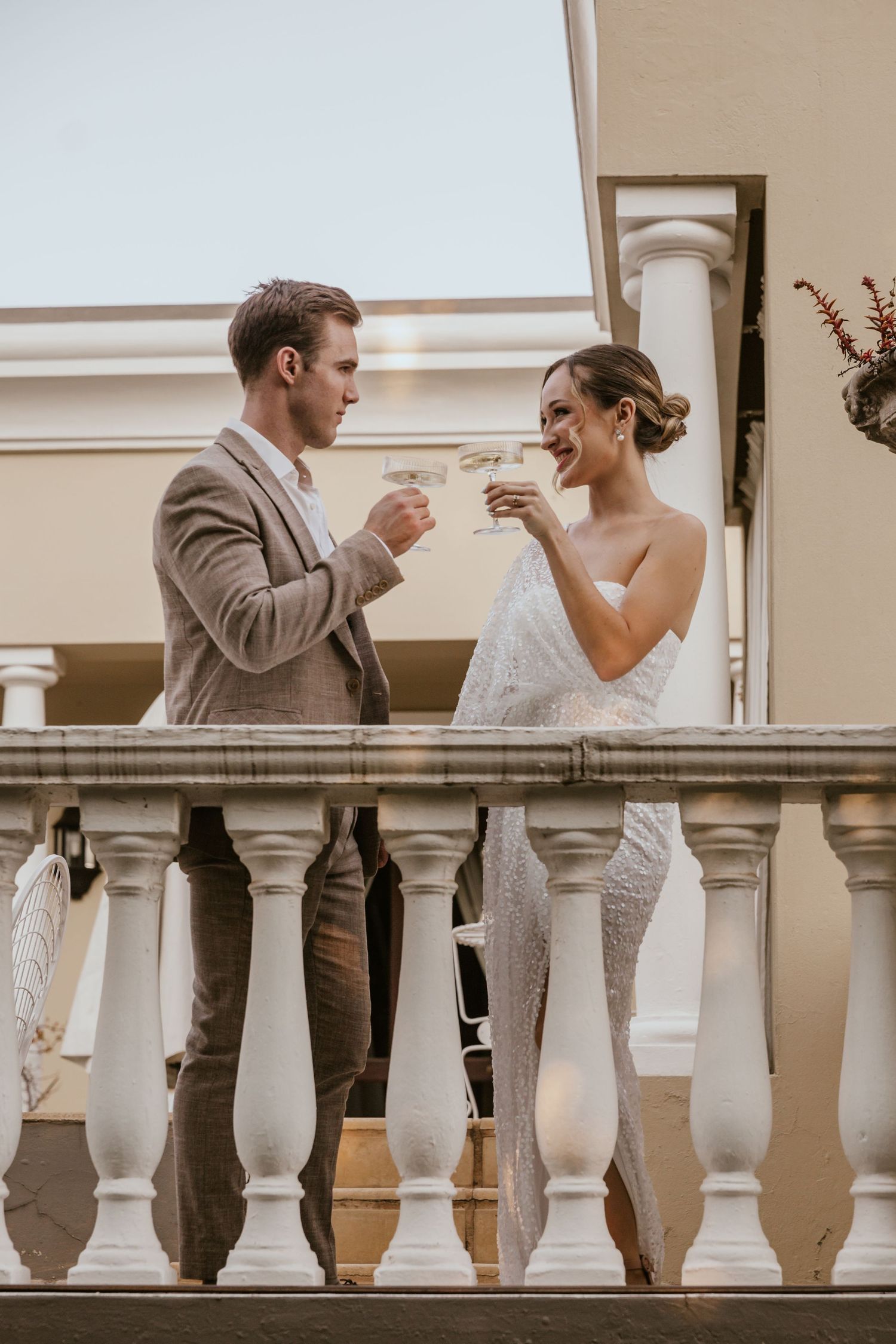 Couple toasting with champagne glasses on an elegant balcony.