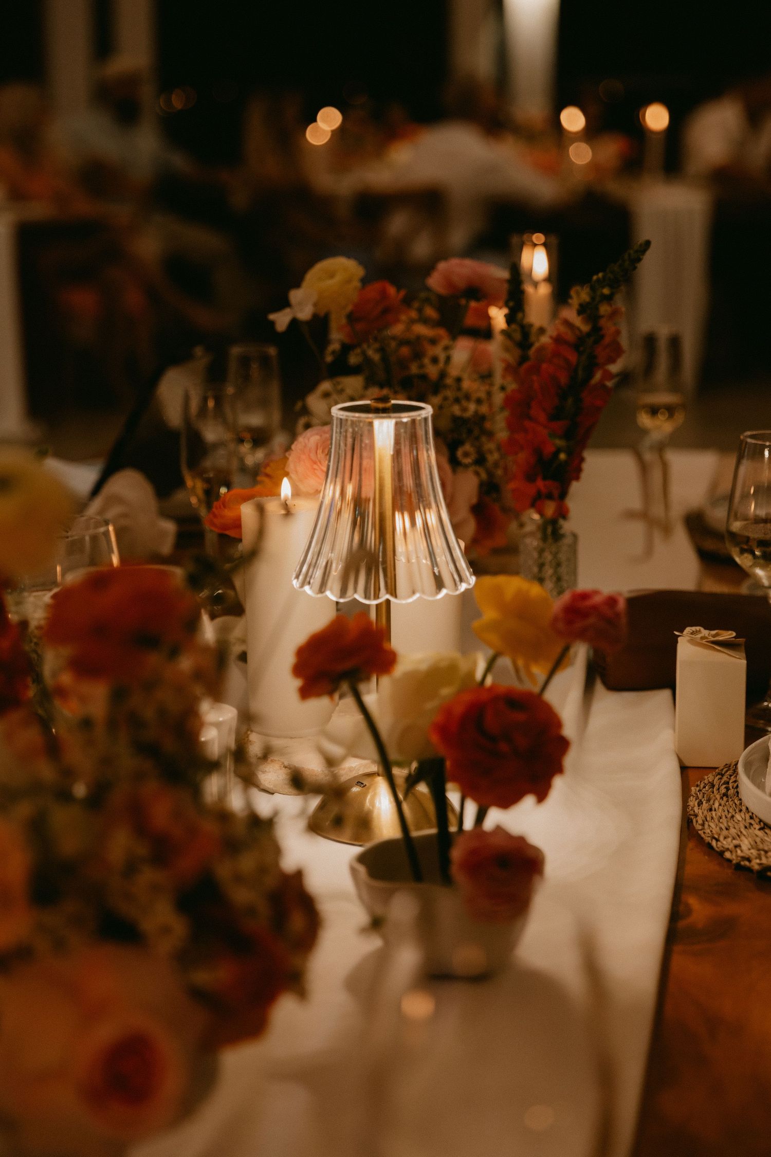 Elegant wedding reception tables decorated with floral centerpieces and glowing candlelight create a romantic ambiance.