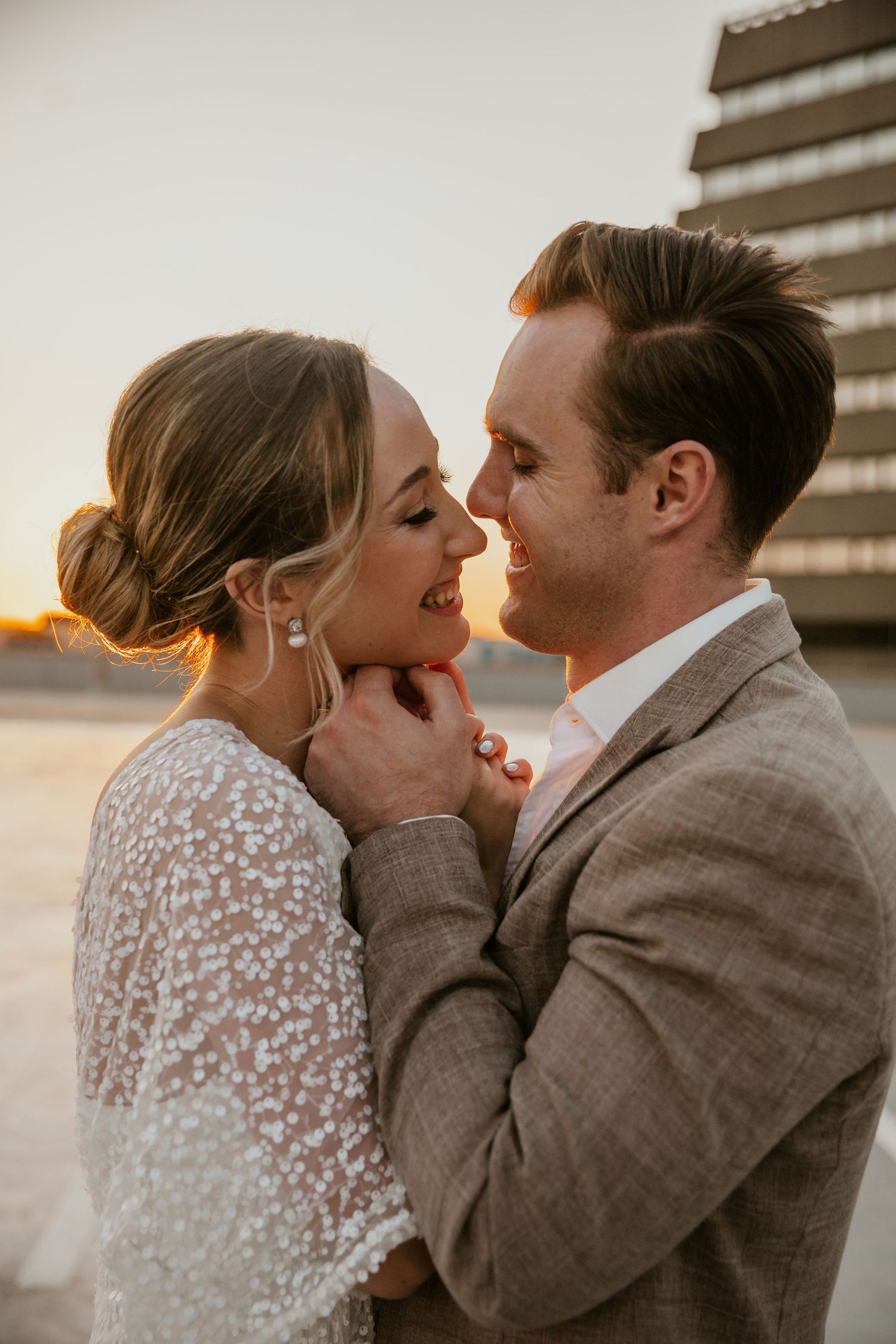 An intimate moment between newlyweds during golden hour on a city rooftop.