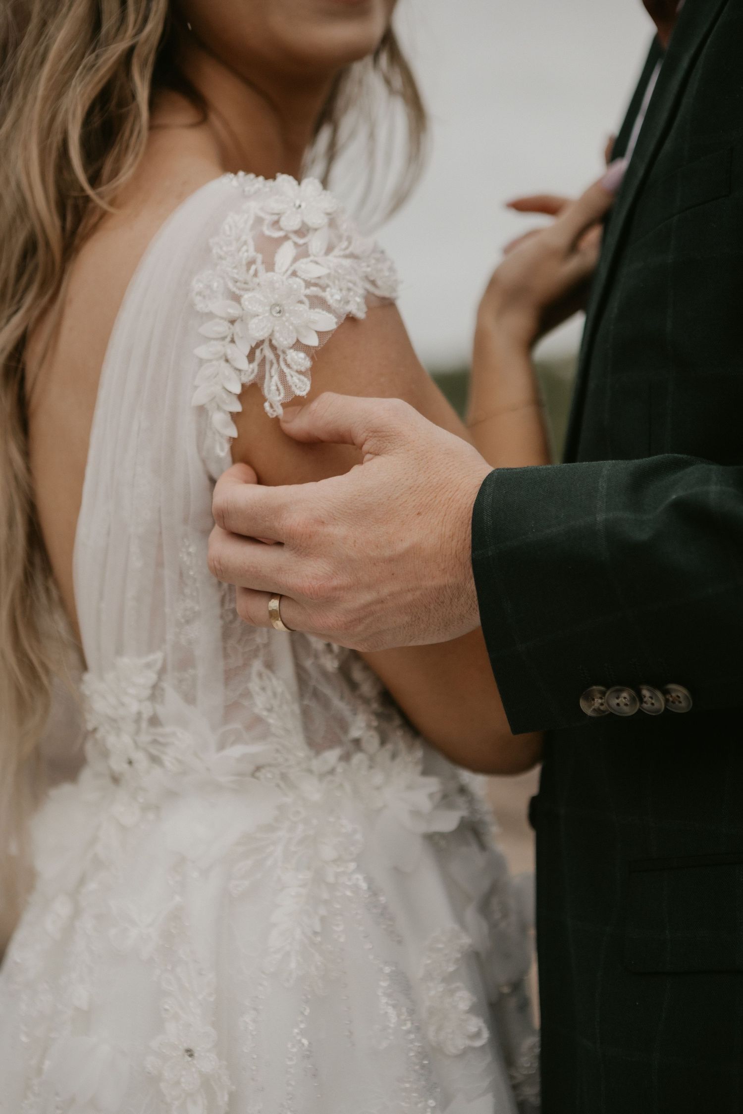 Close-up details of delicate white lace and floral appliques on a wedding dress bodice.