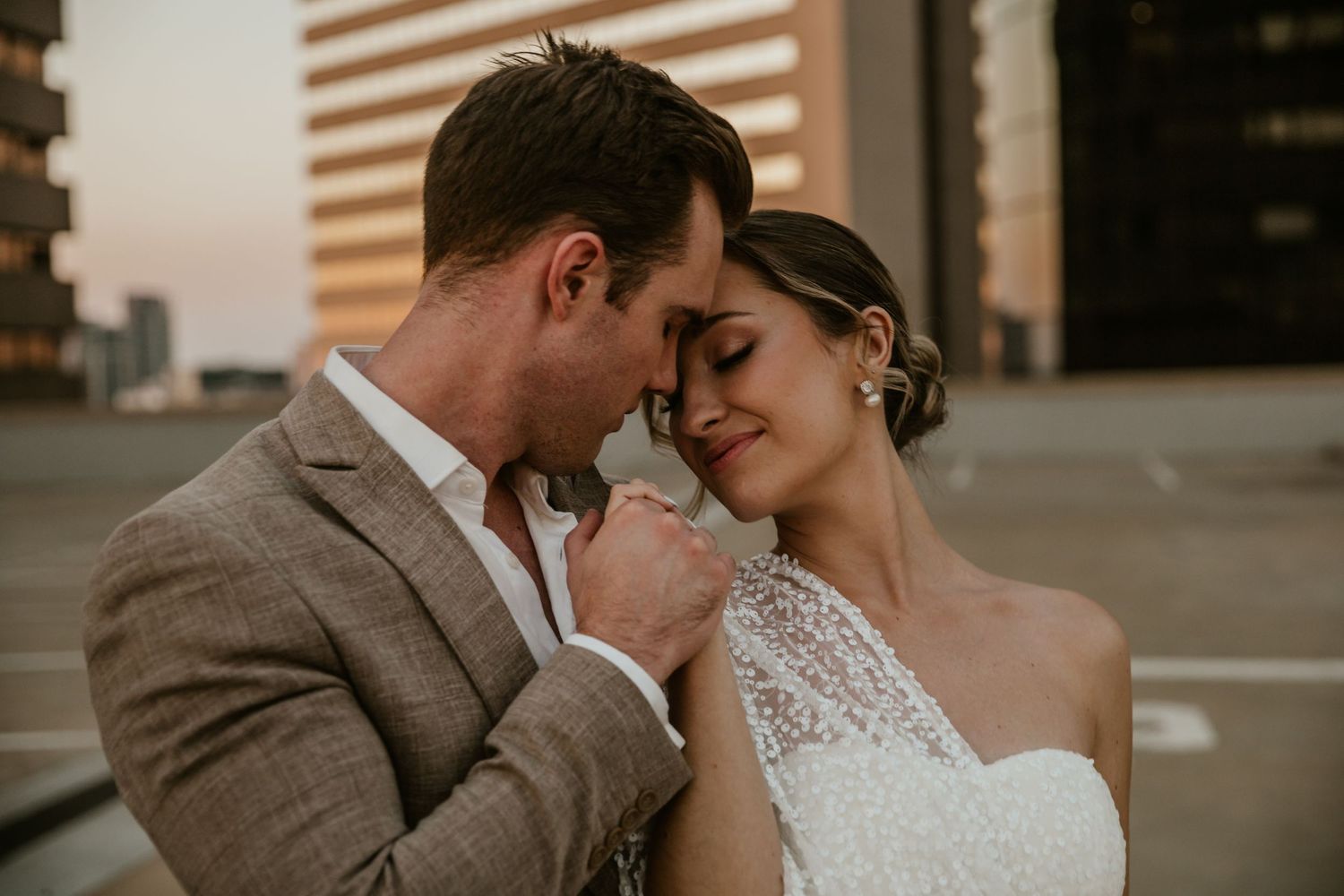 Intimate moment between newlyweds on urban rooftop at sunset.