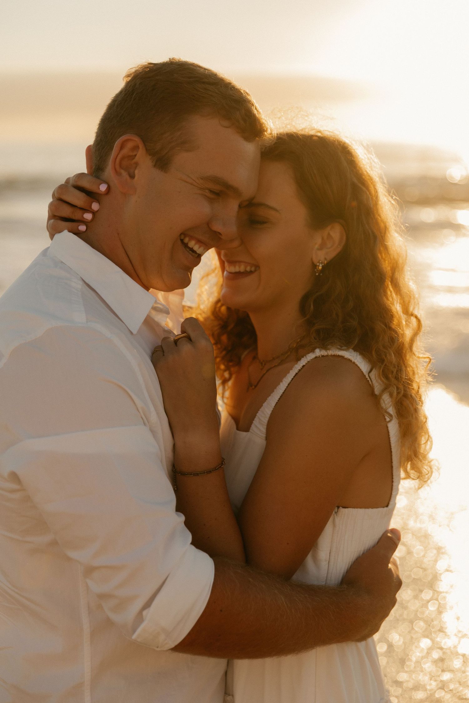 A tender moment shared between a couple on the beach at golden hour.