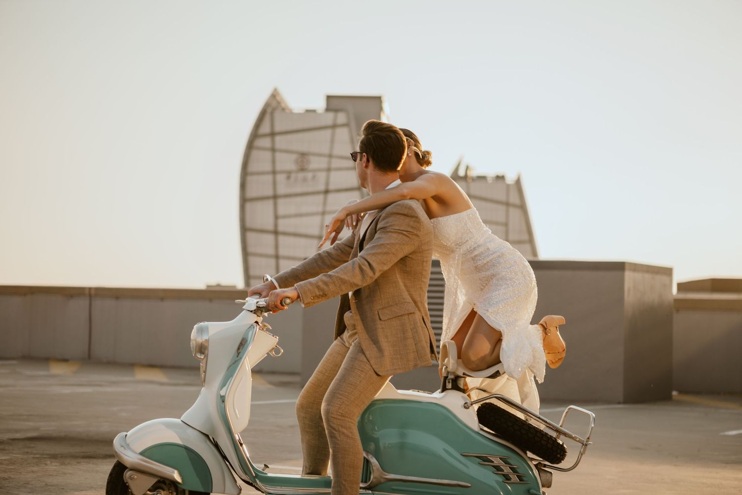 A stylish couple rides a mint green vintage scooter on an urban rooftop.
