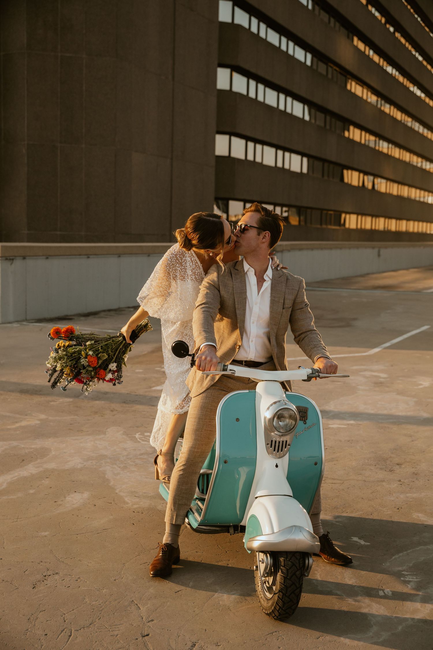 Couple sharing romantic moment on turquoise vintage scooter at sunset.