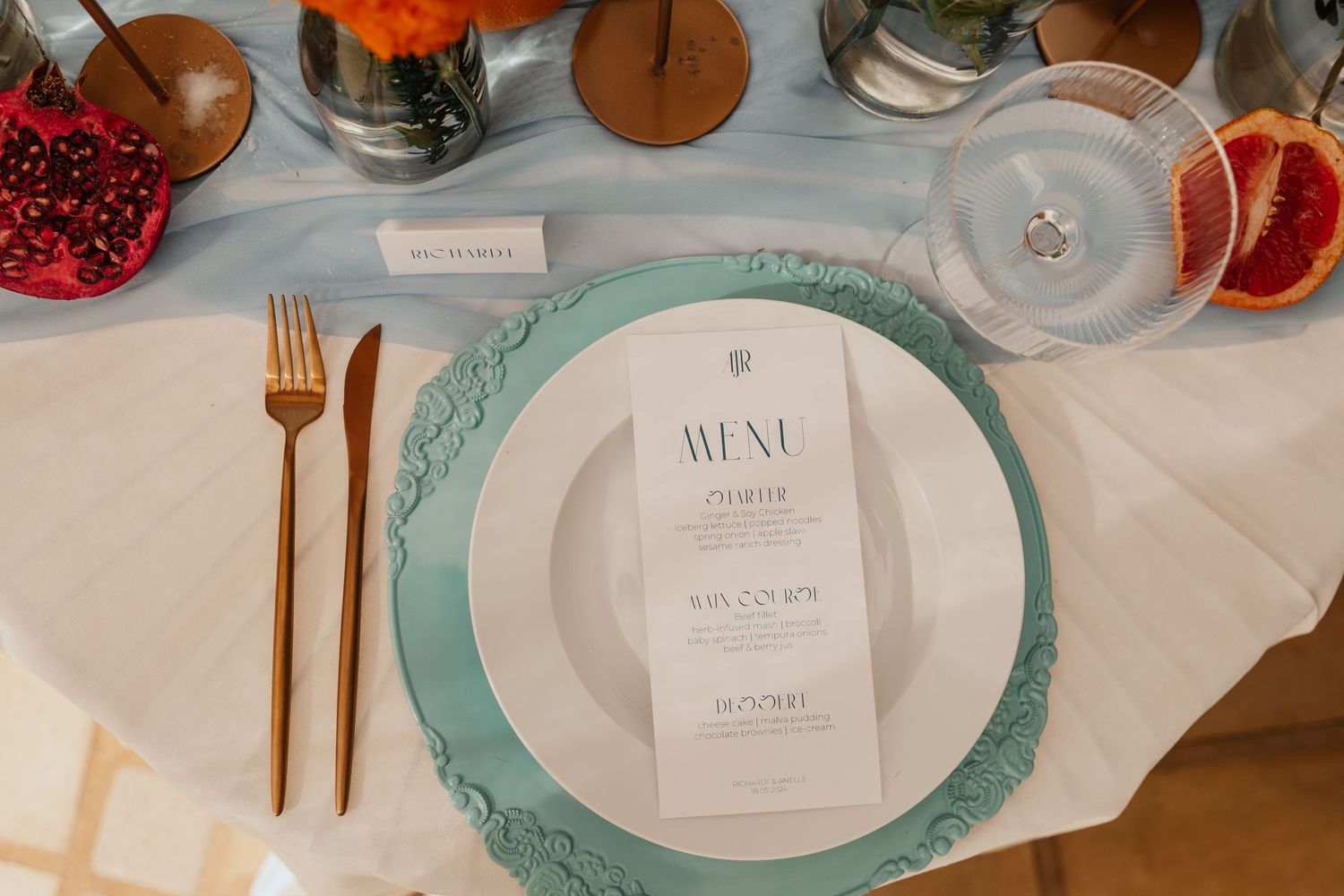 Overhead view of elegant place setting with turquoise charger plate and gold flatware.