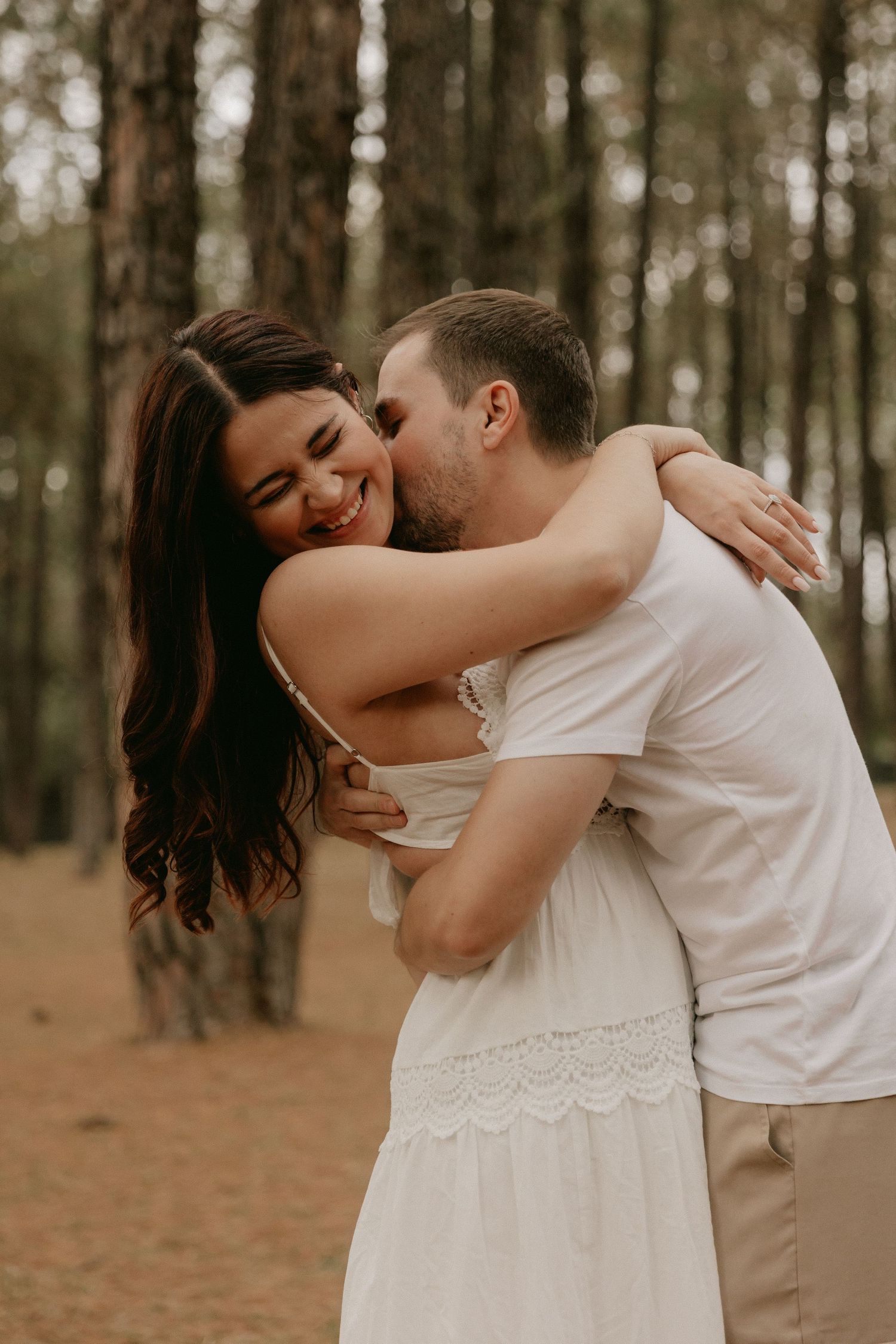 A couple shares intimate dance moves in a romantic forest setting during a photo session.
