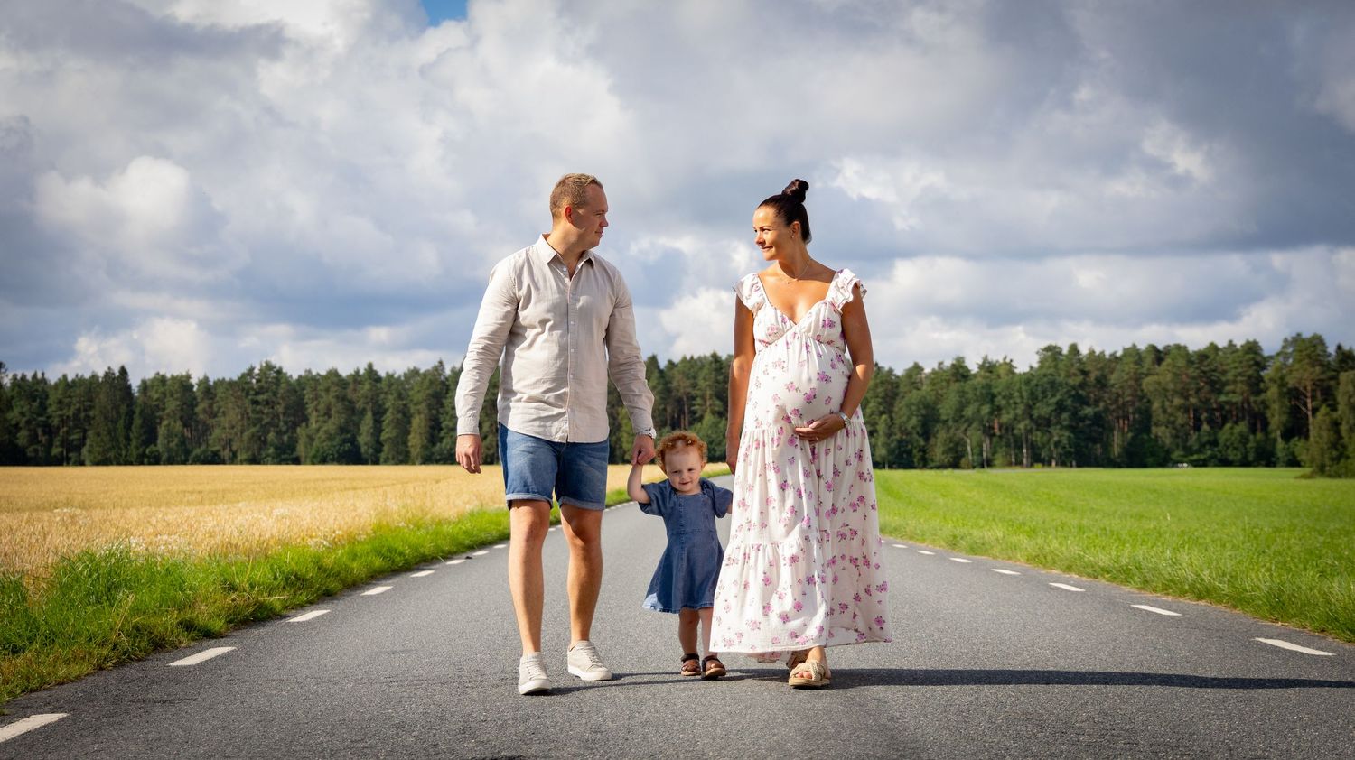 Gravid familj promenera på landsväg mellan åkrar i Varnum - dokumentärt familjefotografering i naturligt ljus.
