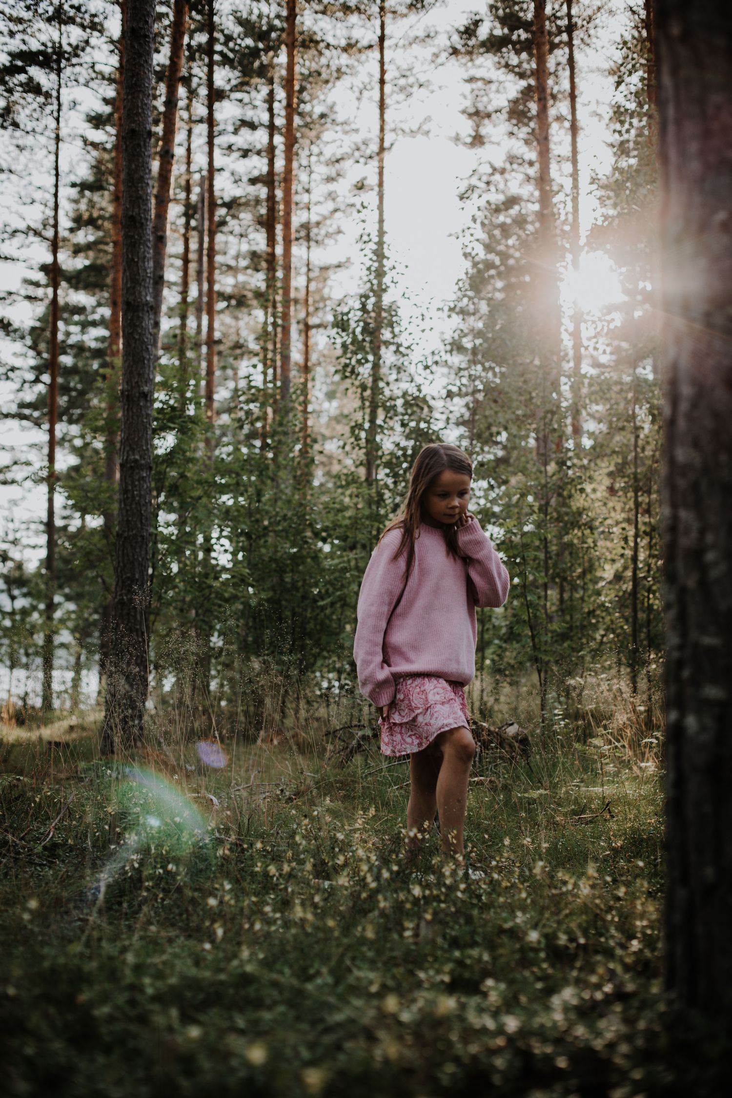 Ett barn som promenerar i skogen vid kvällssolen i en avslappnad porträttfotografering.