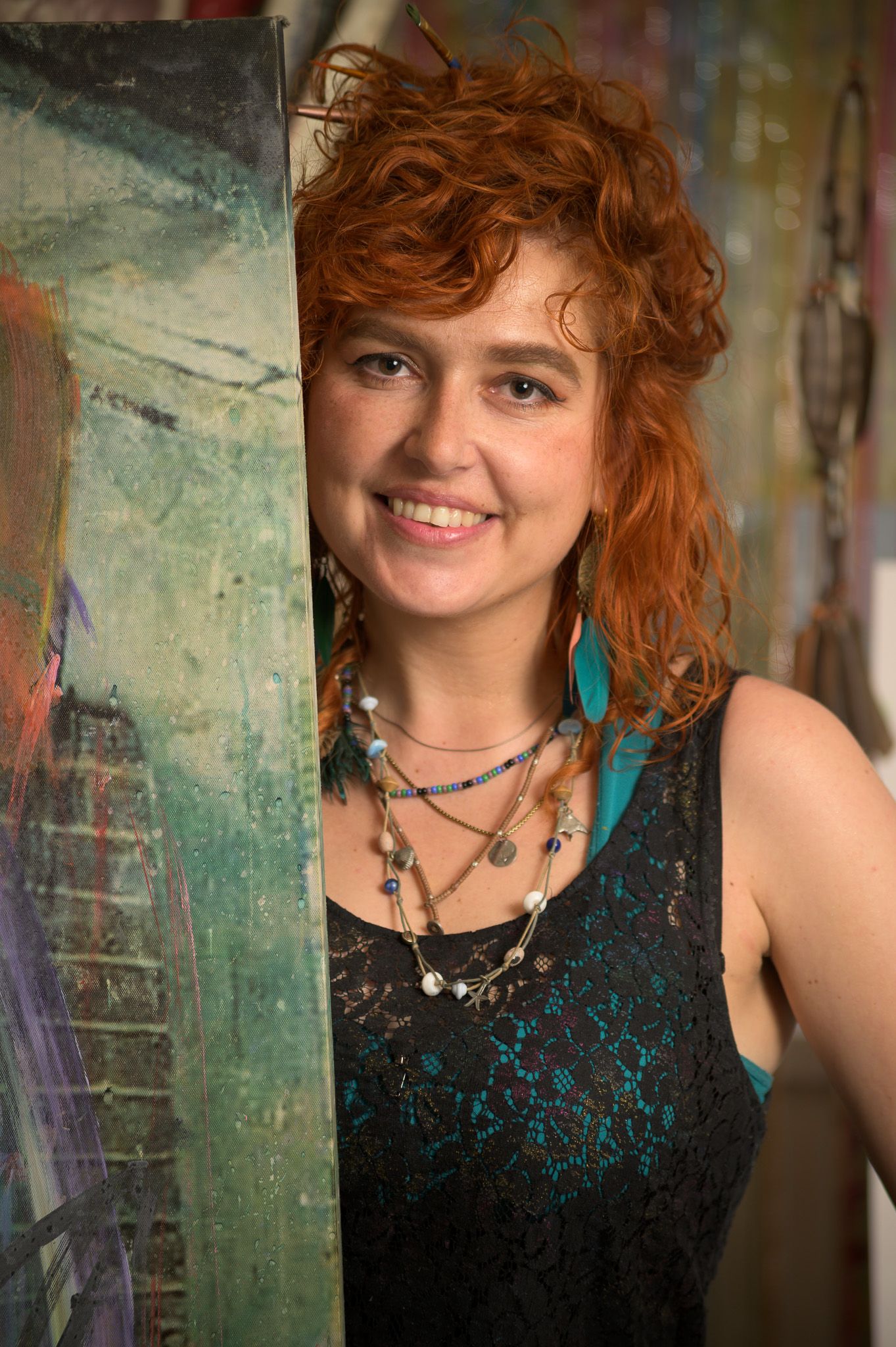 Portrait in bohemian style with turquoise earrings and layered necklaces against a textured wall.