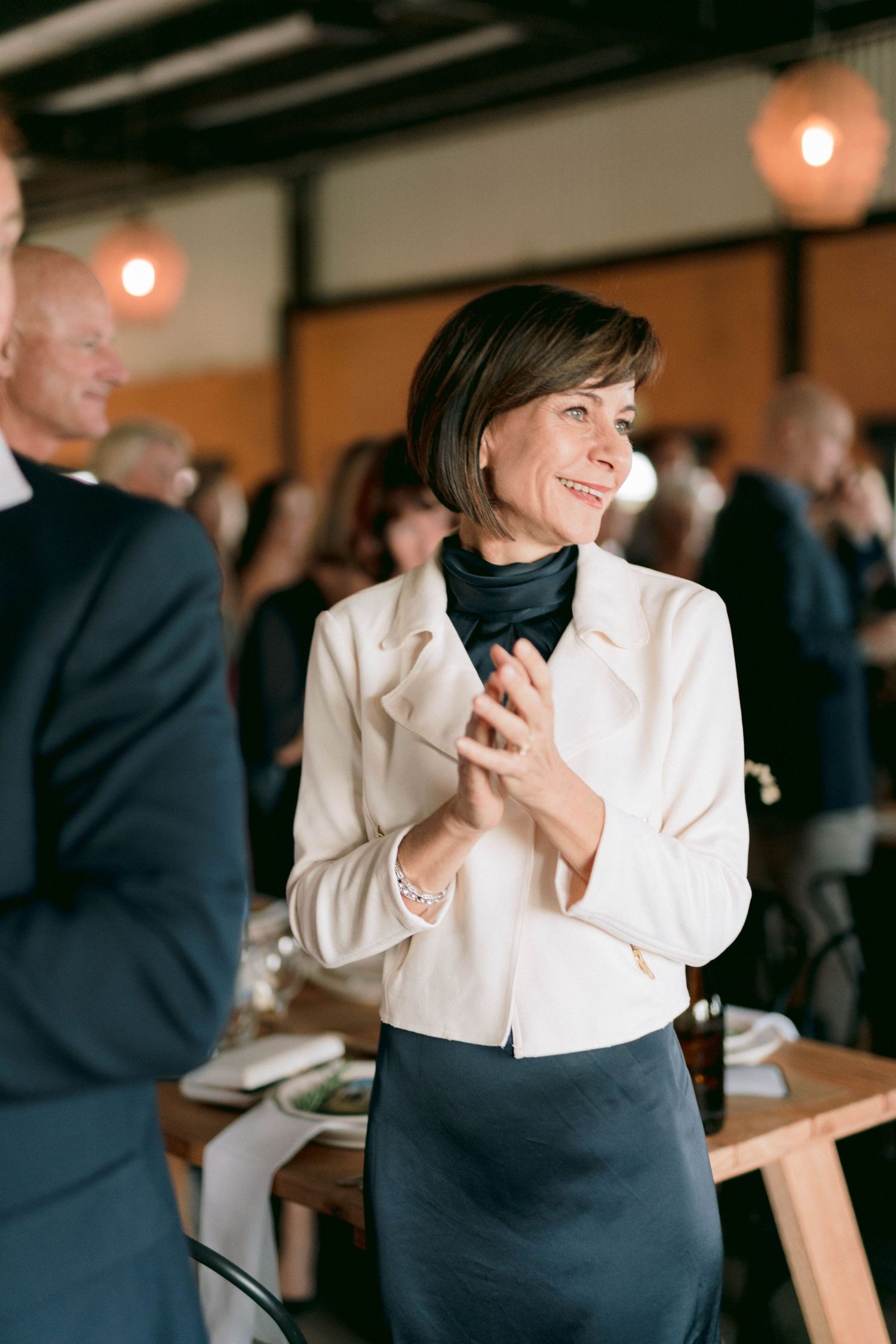 Guest in elegant black and white attire enjoying reception in warm indoor lighting.