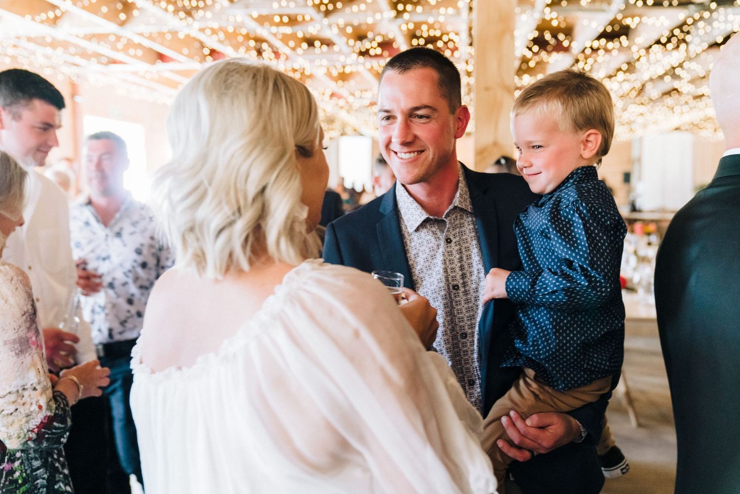 Candid wedding reception moment with guests sharing joyful interaction indoors.