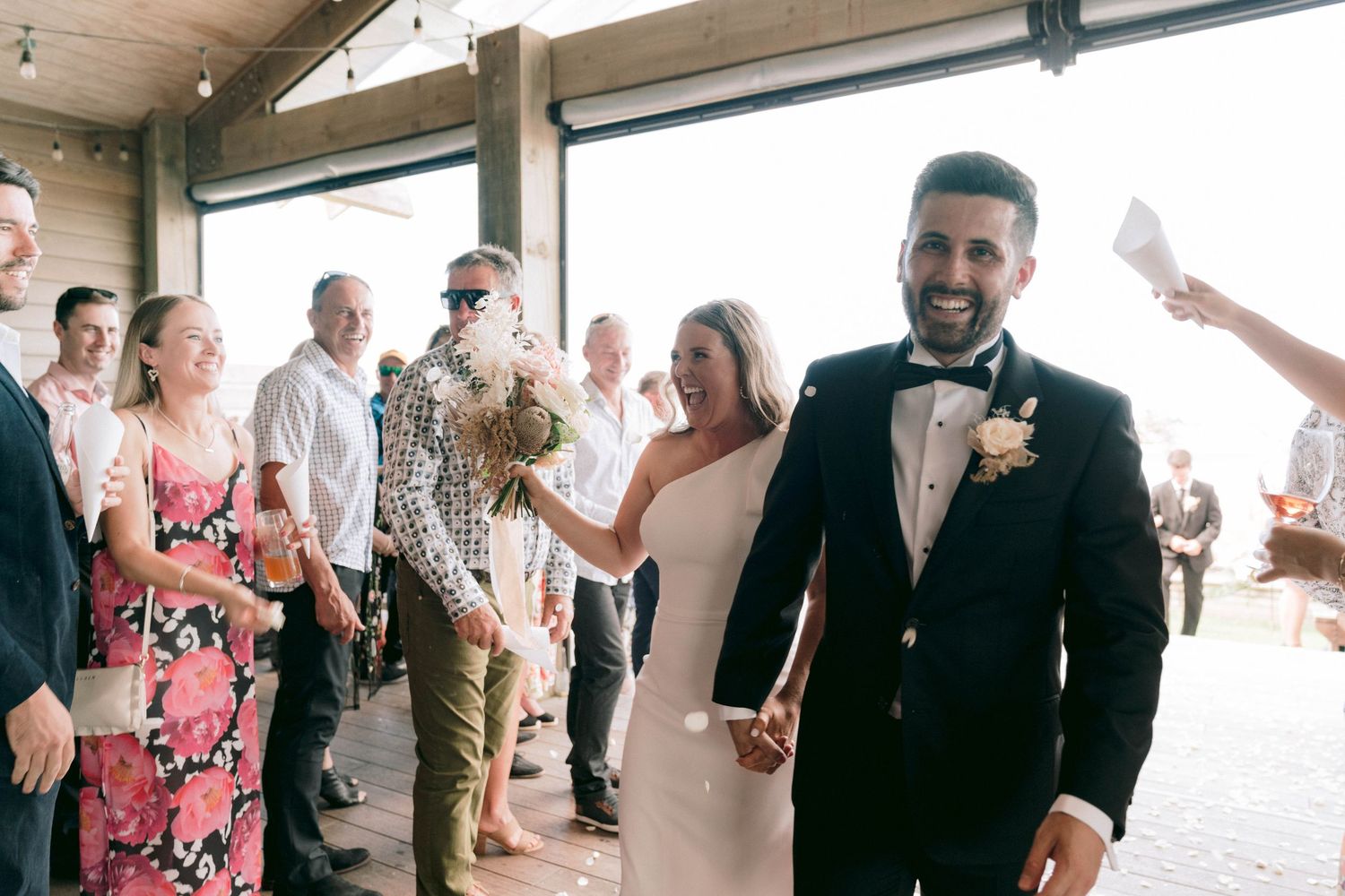 Wedding celebration in progress with guests cheering in an indoor venue with natural lighting.