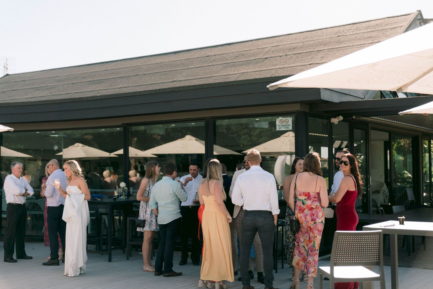 Wedding reception venue exterior with covered patio area and guests mingling.
