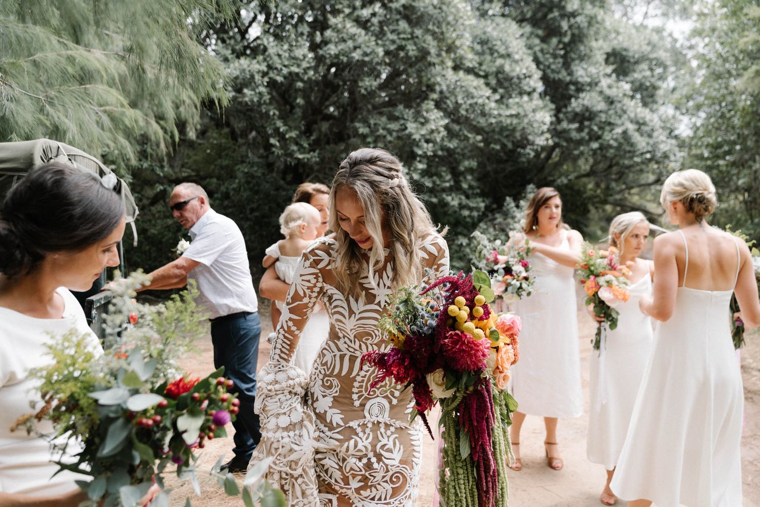 Wedding guests celebrate outdoors with vibrant bouquets and white dresses during a summer garden party celebration.