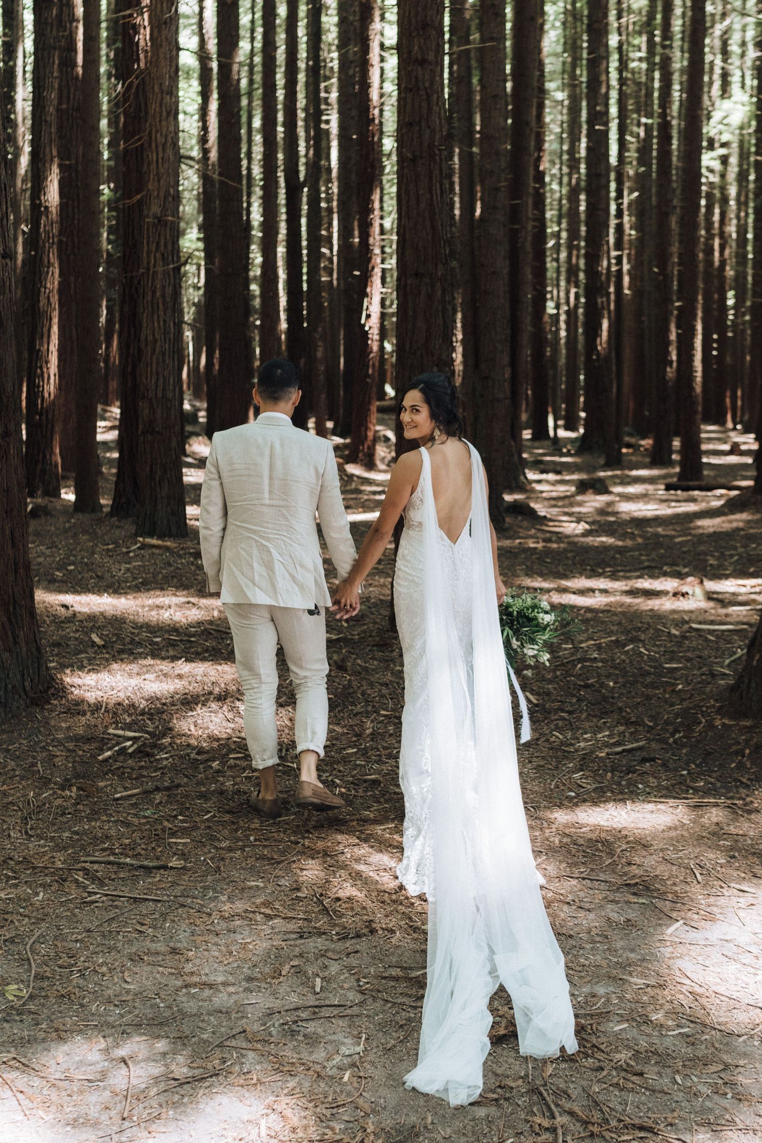 Romantic walk through a majestic redwood forest in white wedding attire.