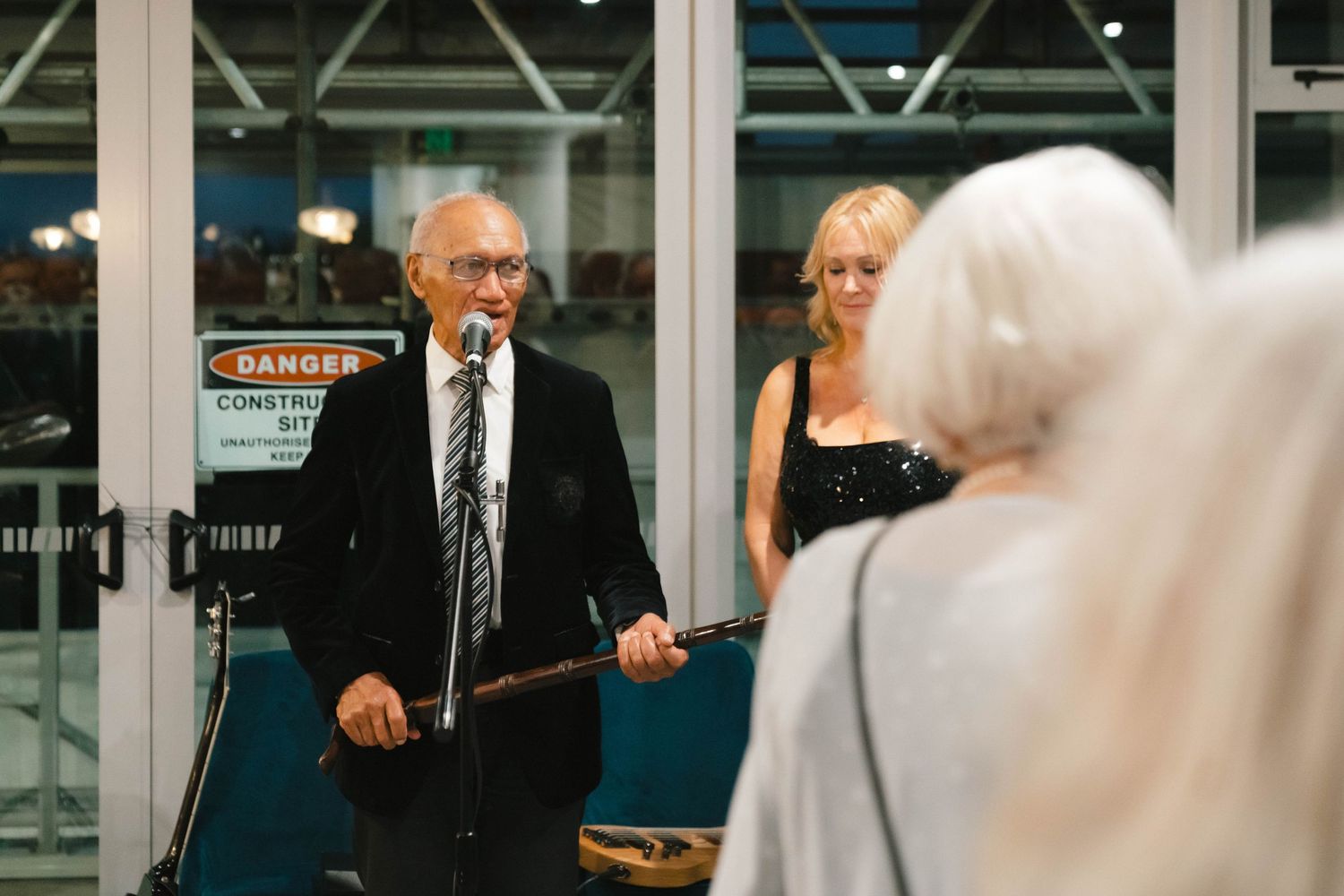 People standing in a line with formal attire at an indoor venue.