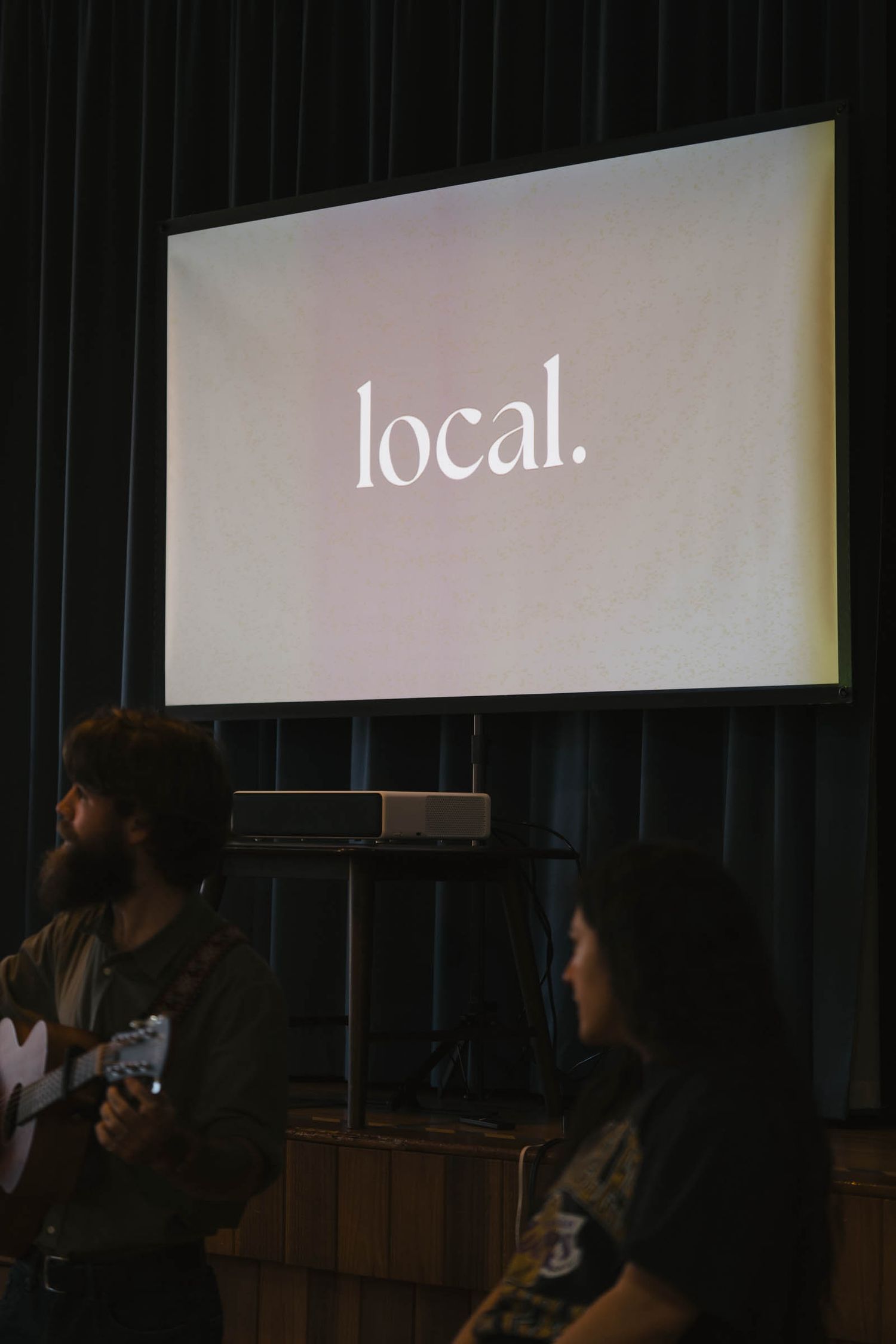 Dark room with projection screen showing text display.