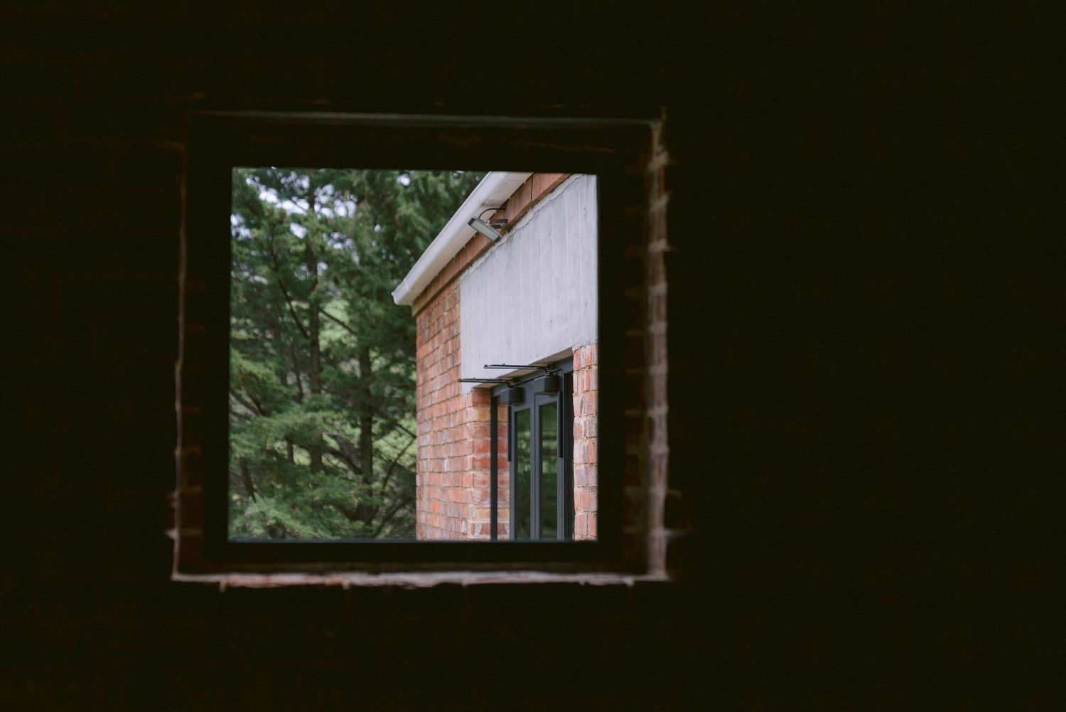 Dark interior view through multiple doorway frames creating a moody architectural perspective.
