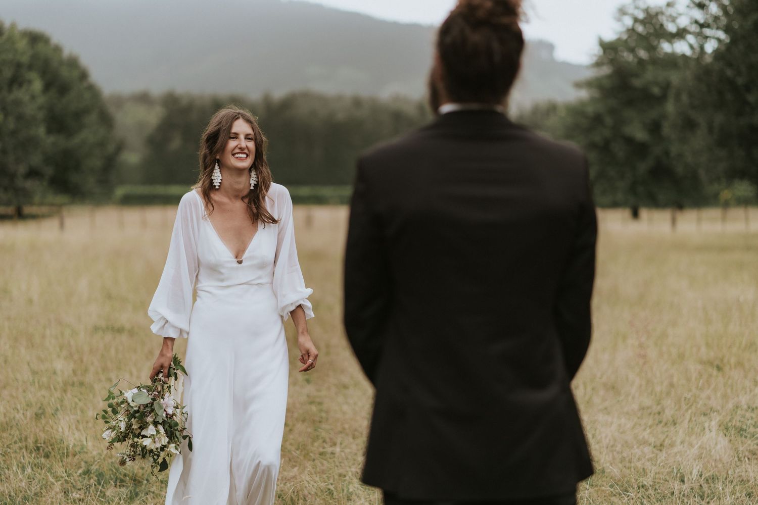 Couple standing in a golden grass field during a rustic outdoor wedding ceremony.