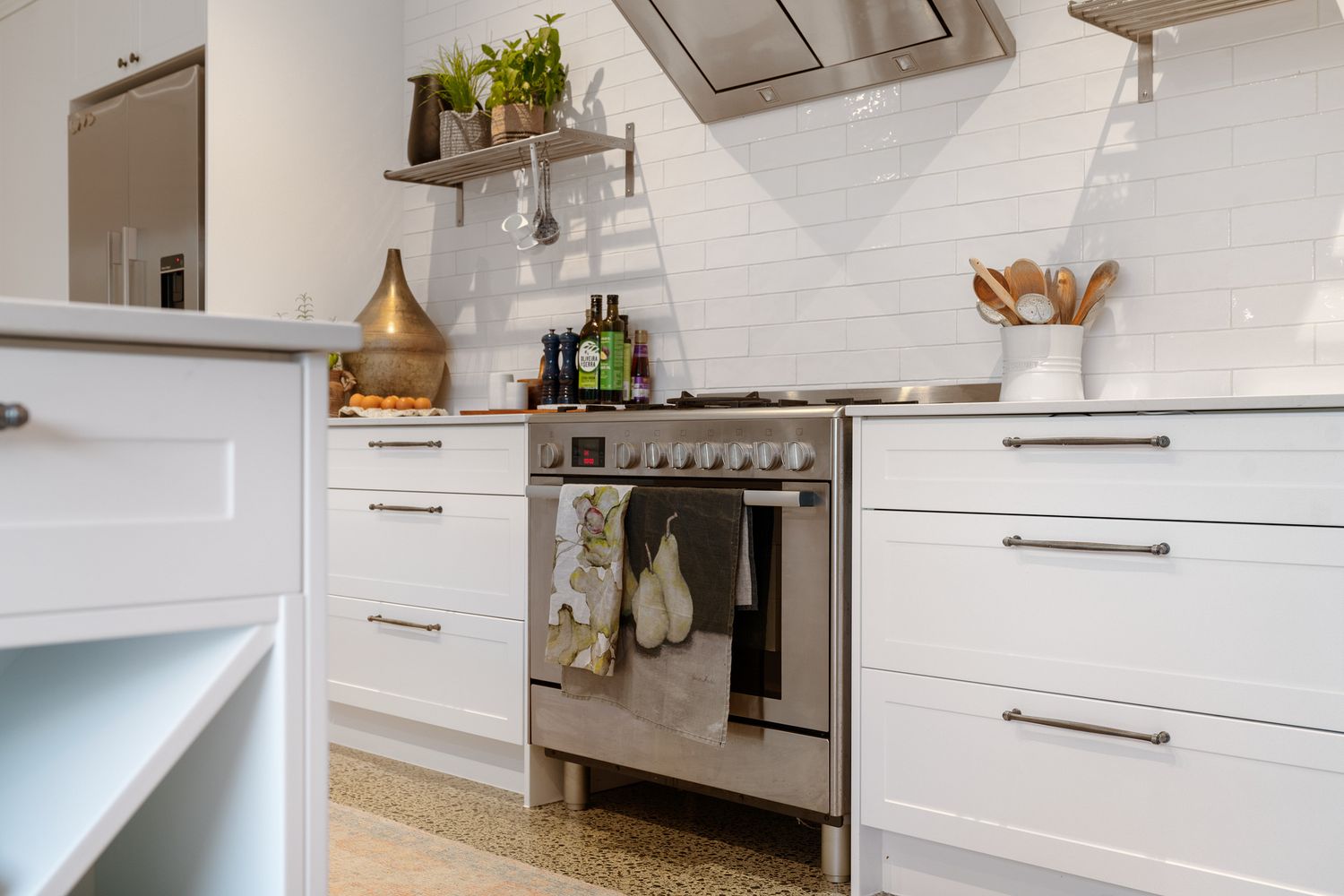 Modern white kitchen featuring stainless steel range and sleek cabinetry with metallic accents.