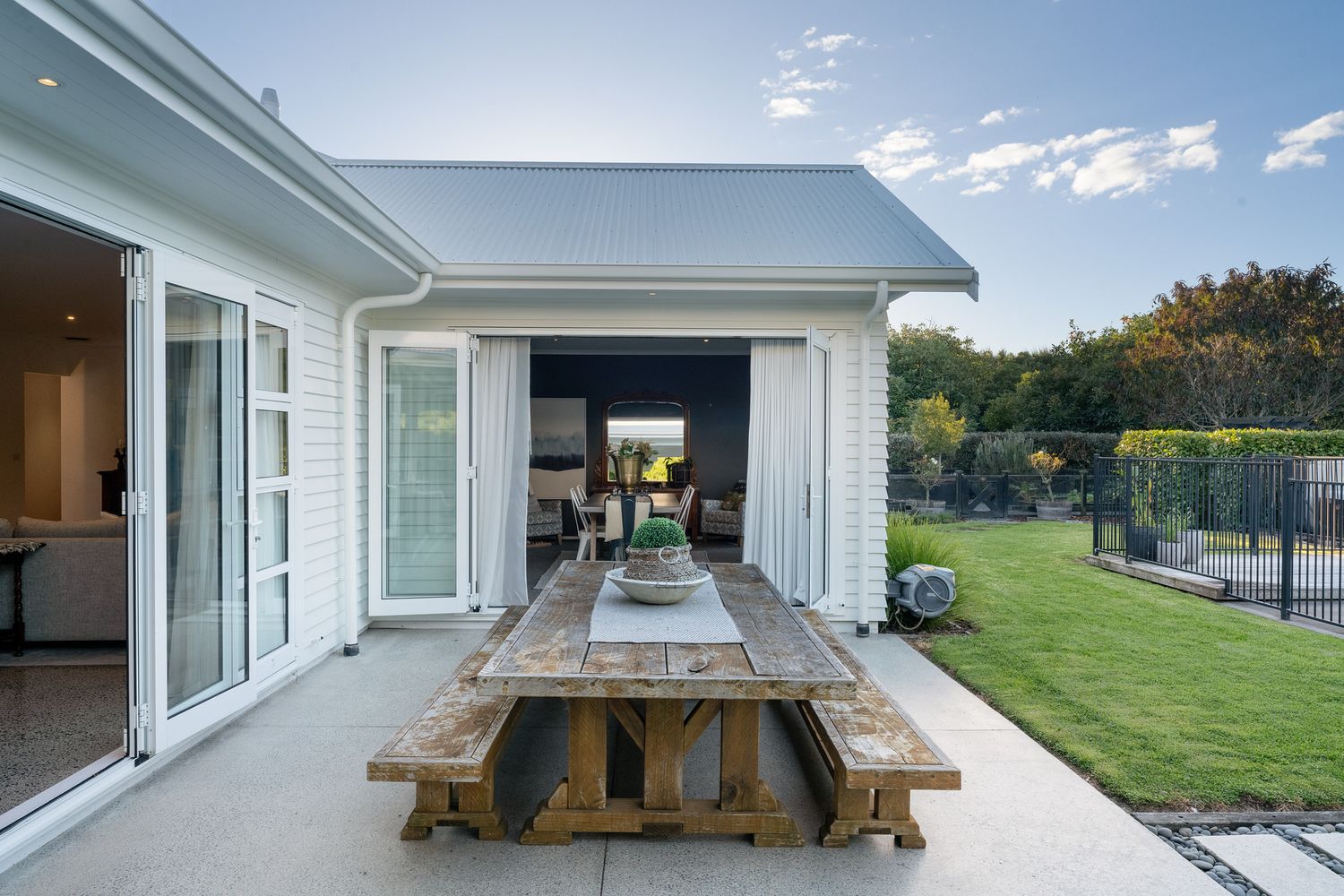 Outdoor living space with wooden picnic tables and views of the pool and landscaped grounds.