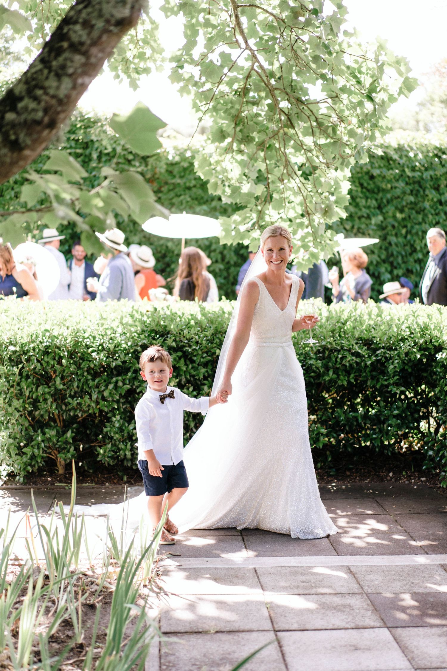 Wedding party plays with a flowing white dress in a garden setting on a sunny afternoon.