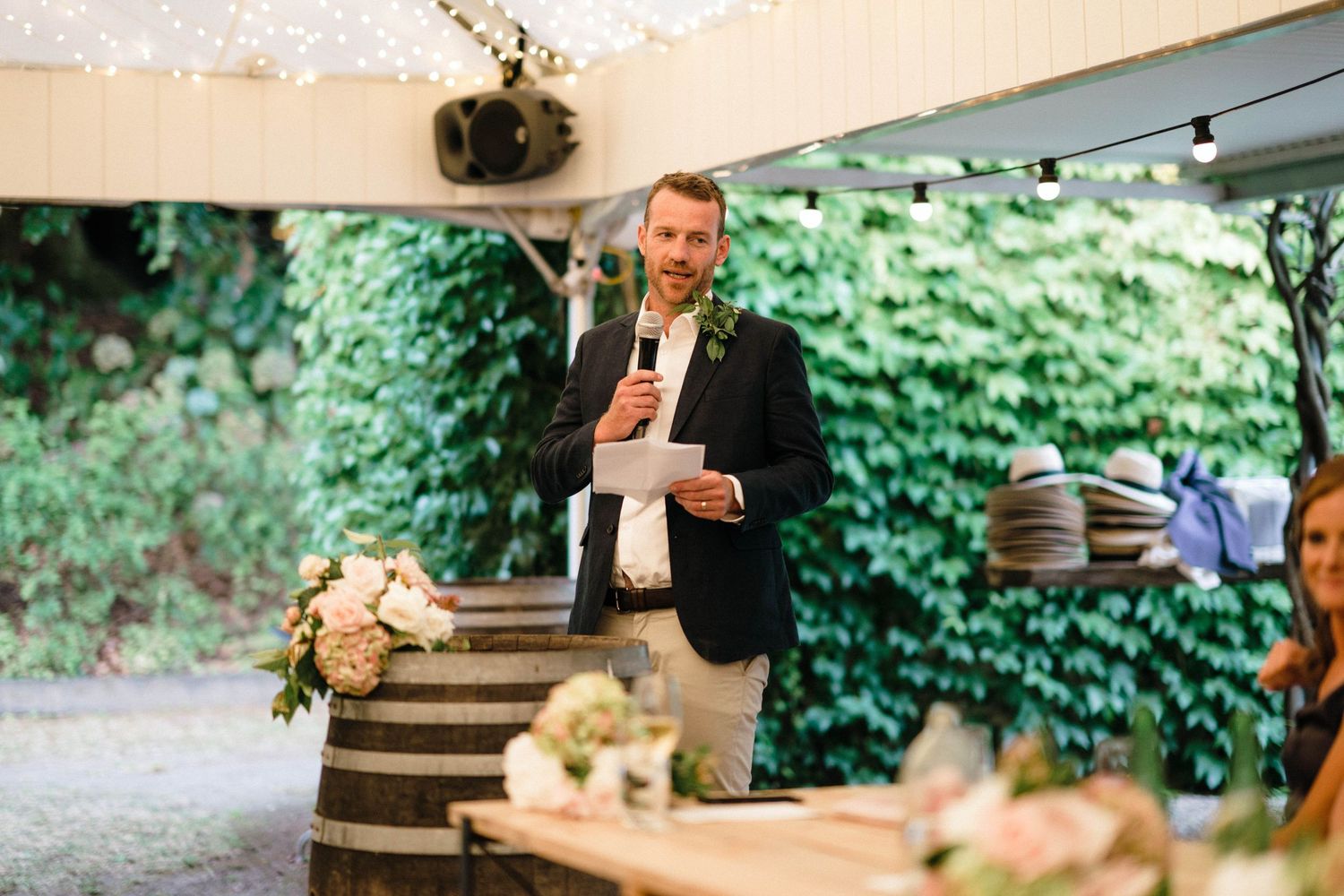 White floral arrangements and string lights decorate an elegant outdoor wedding reception space.